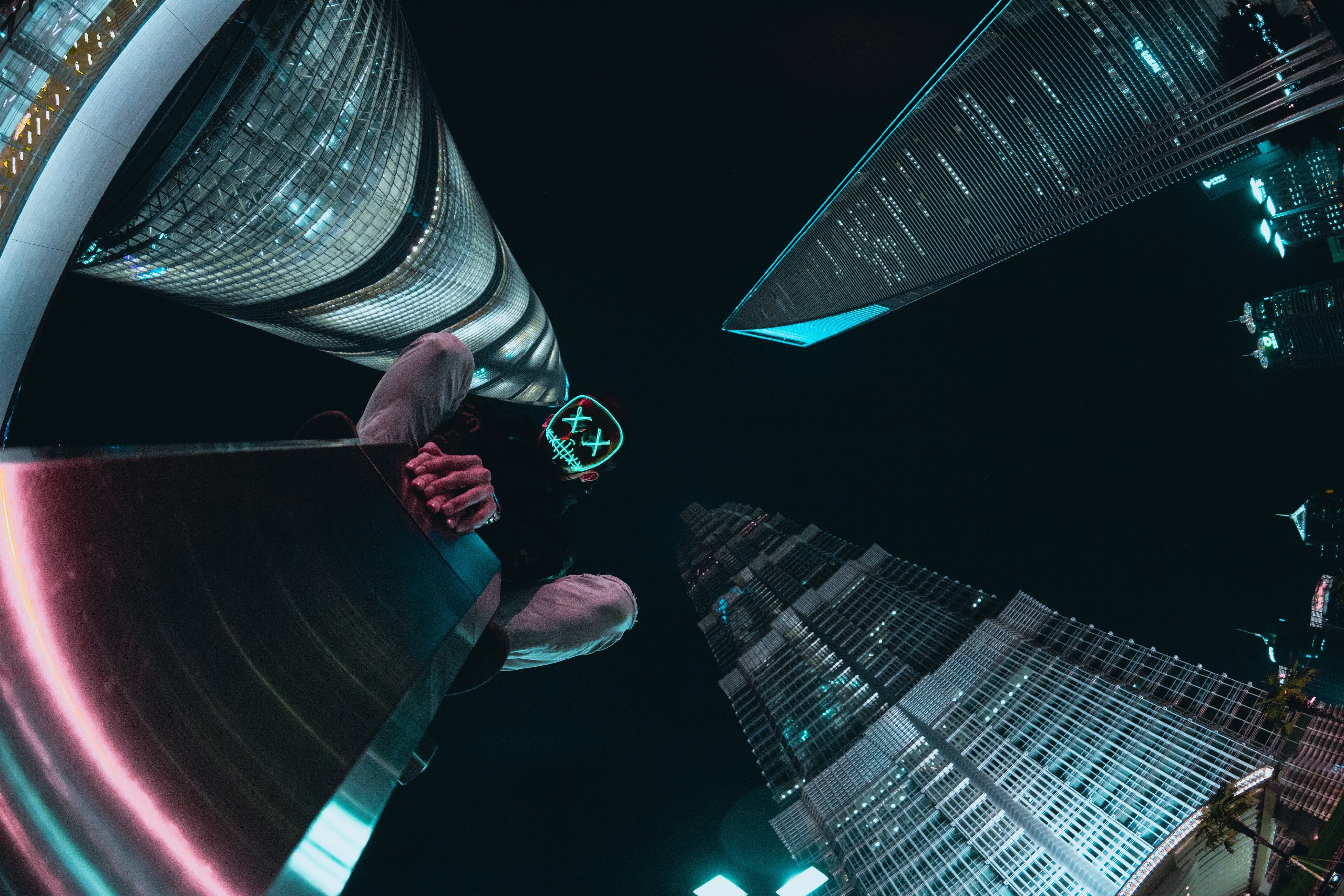 Person in mask looking up at Shanghai skyscrapers at night HD Wallpaper