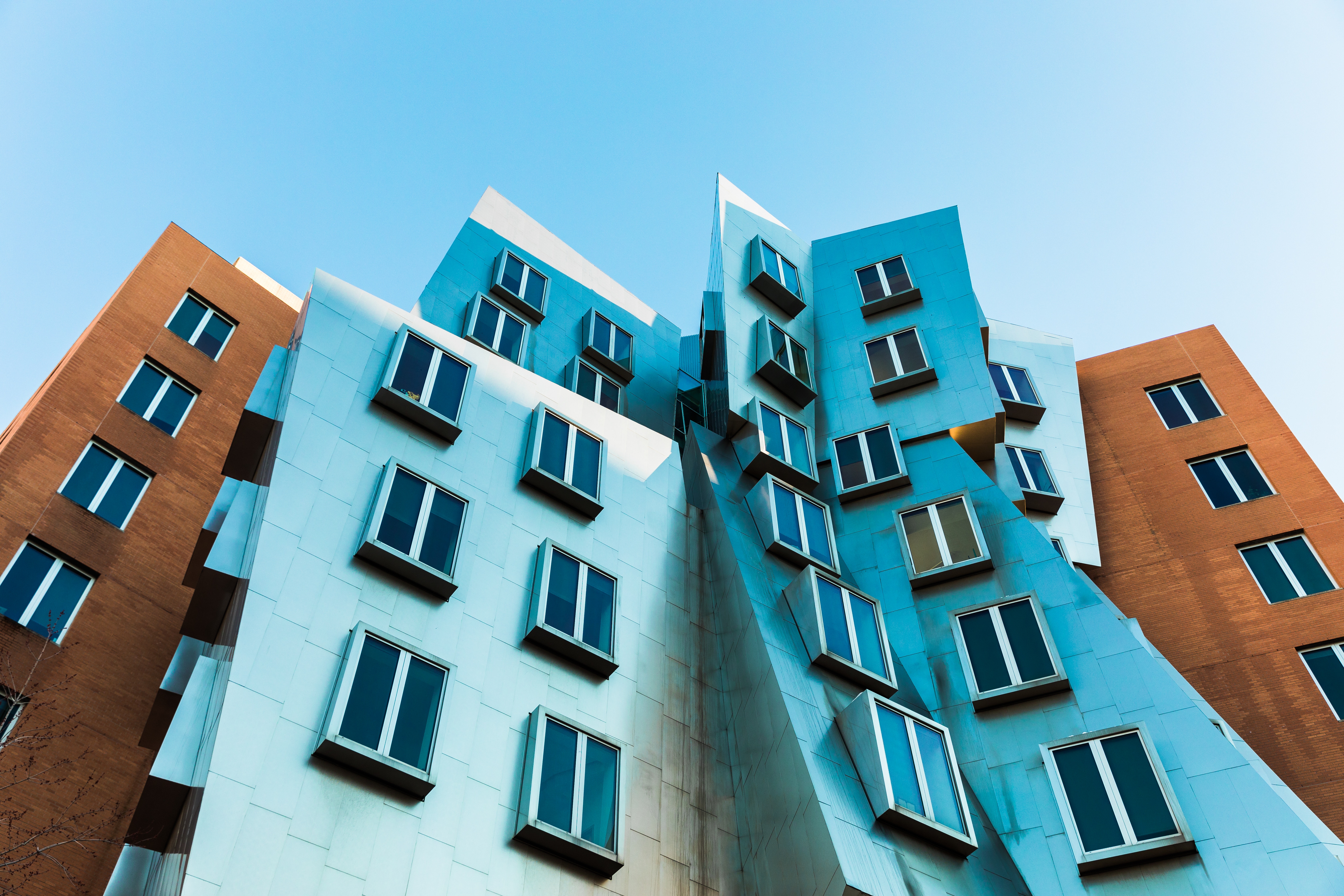 Looking up at a modern building with blue and brown facades HD Wallpaper