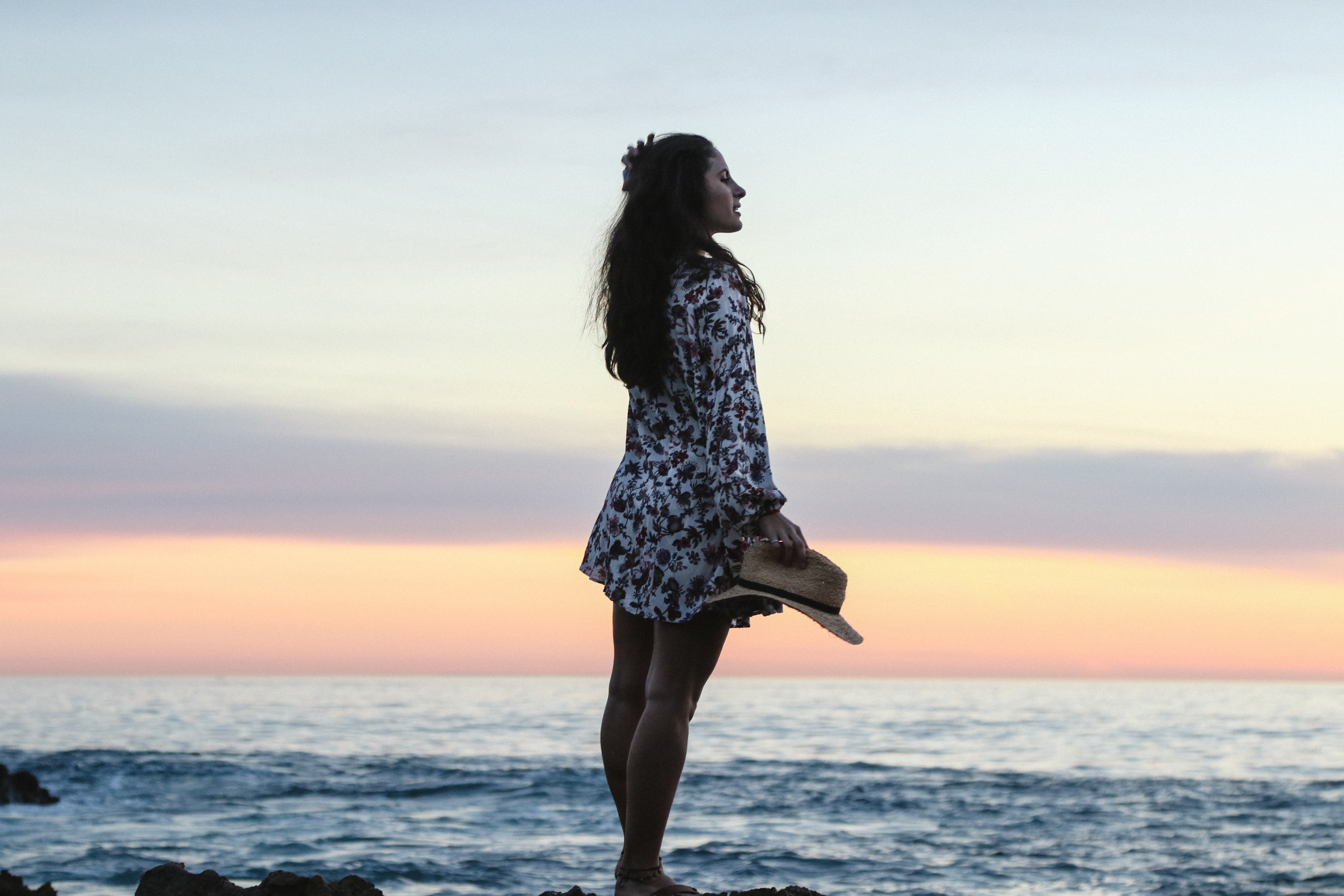 Woman holding a hat at sunset by the ocean HD Wallpaper