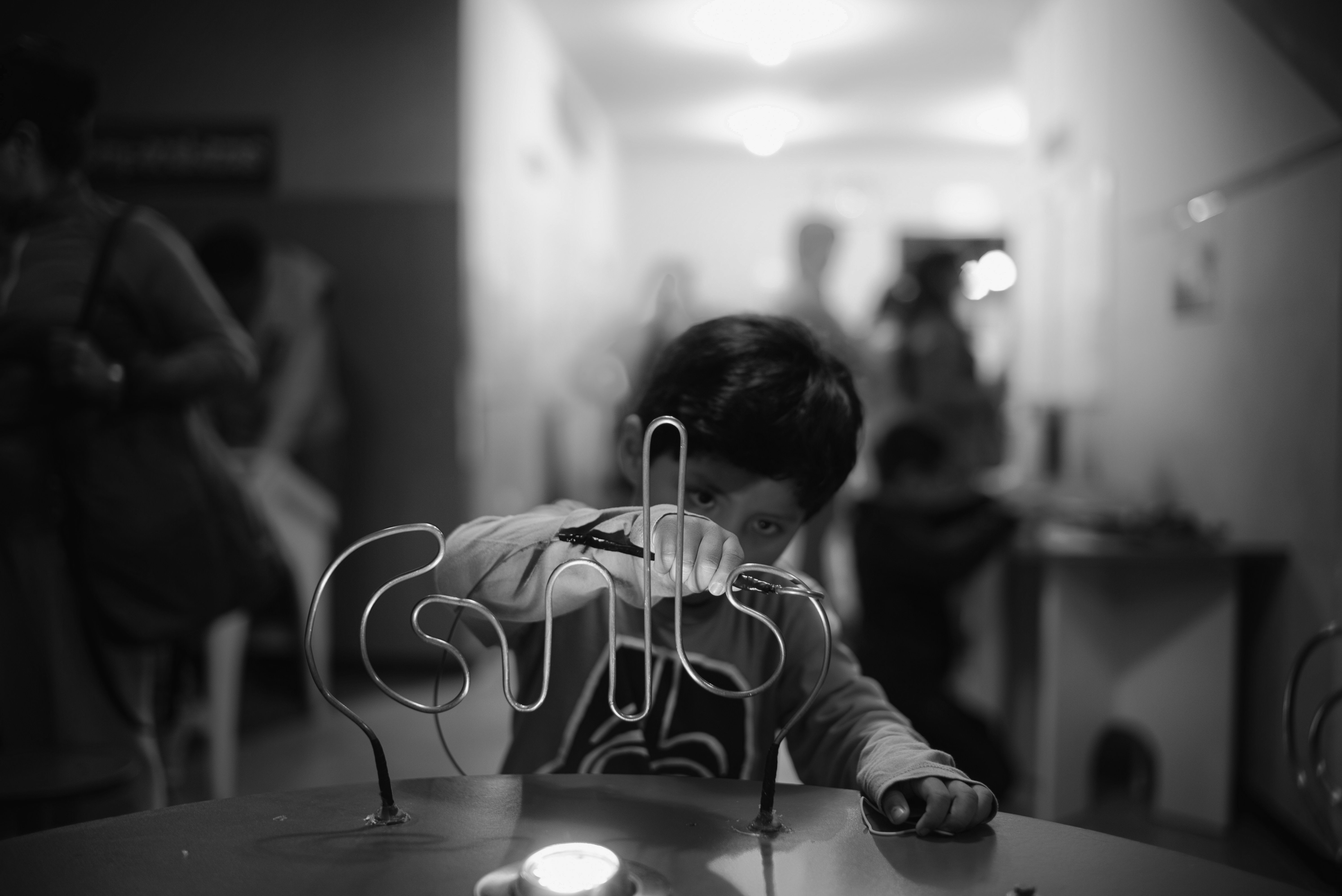Boy plays with a wire maze game HD Wallpaper
