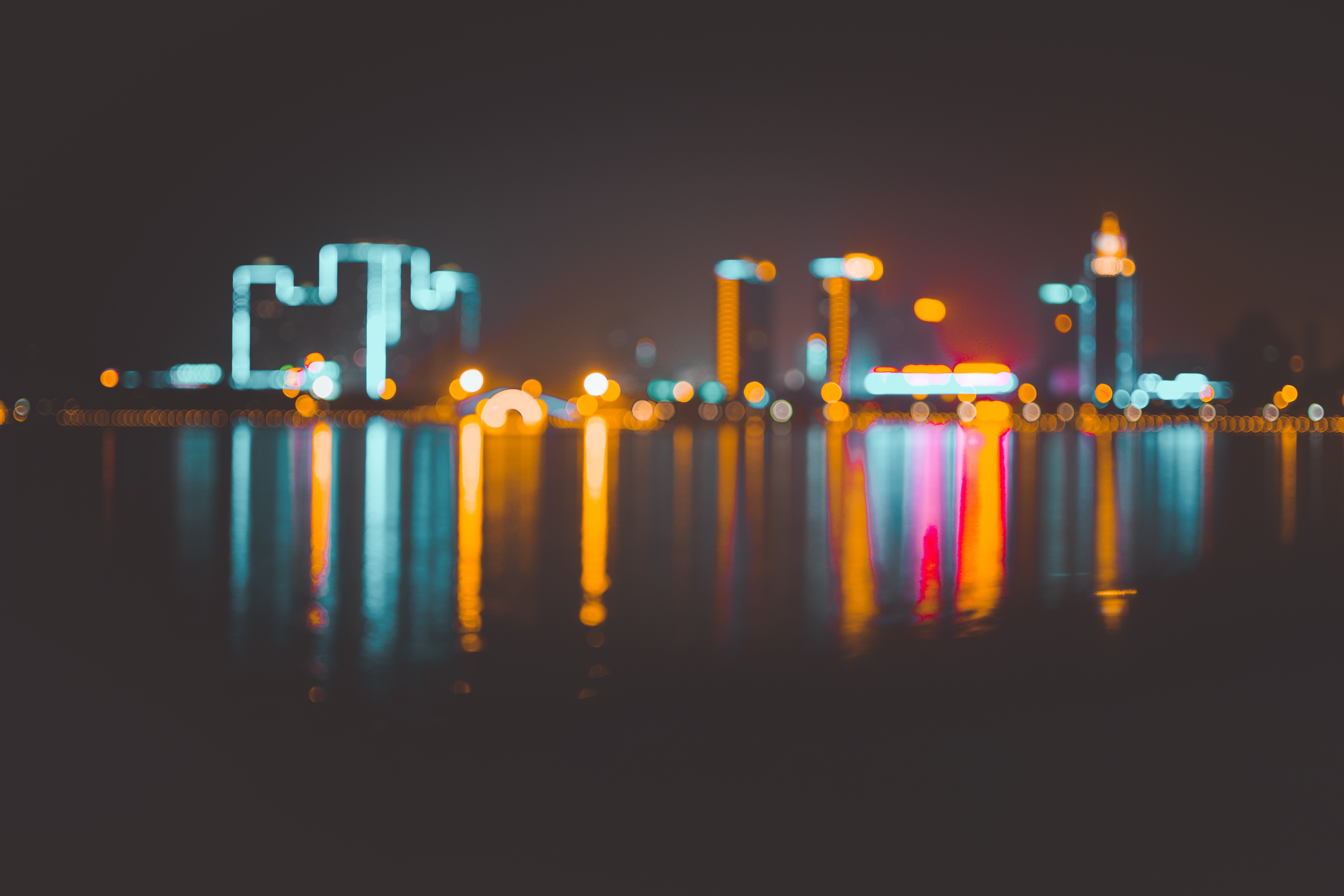 Cityscape with bokeh lights reflected on water at night HD Wallpaper