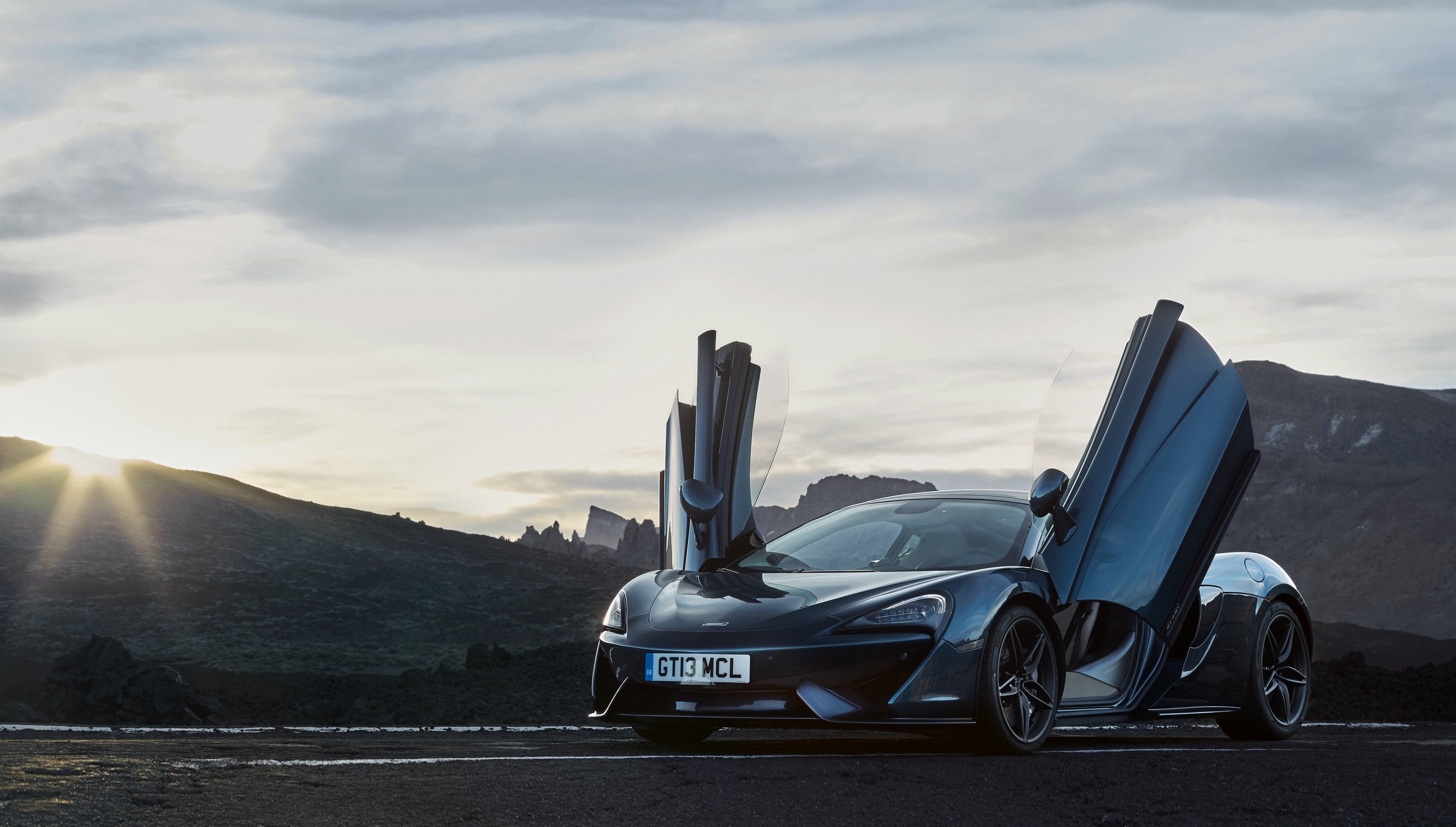 McLaren 570S with butterfly doors in a mountainous landscape HD Wallpaper