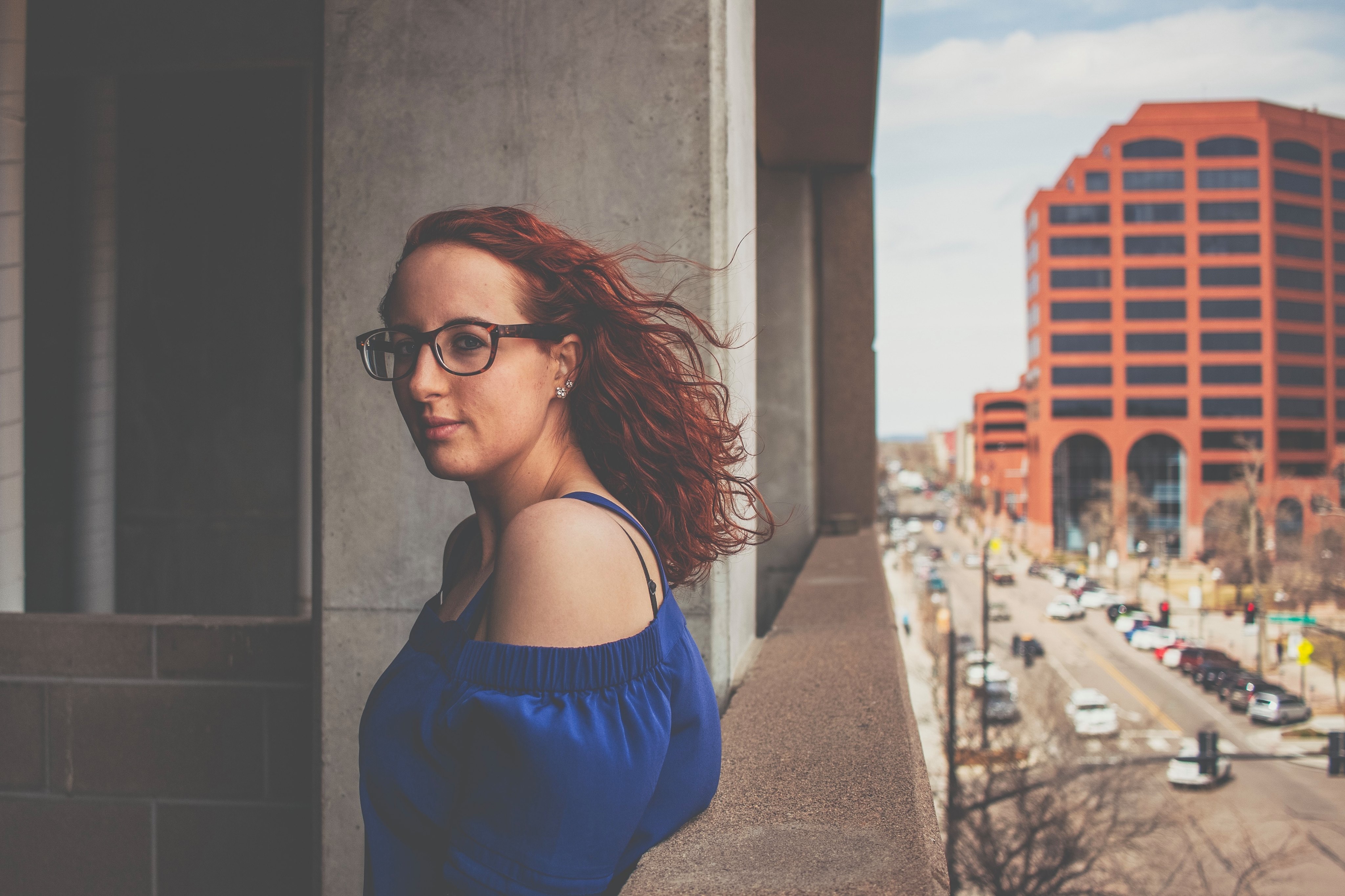 Woman with red hair on a balcony overlooking a city HD Wallpaper