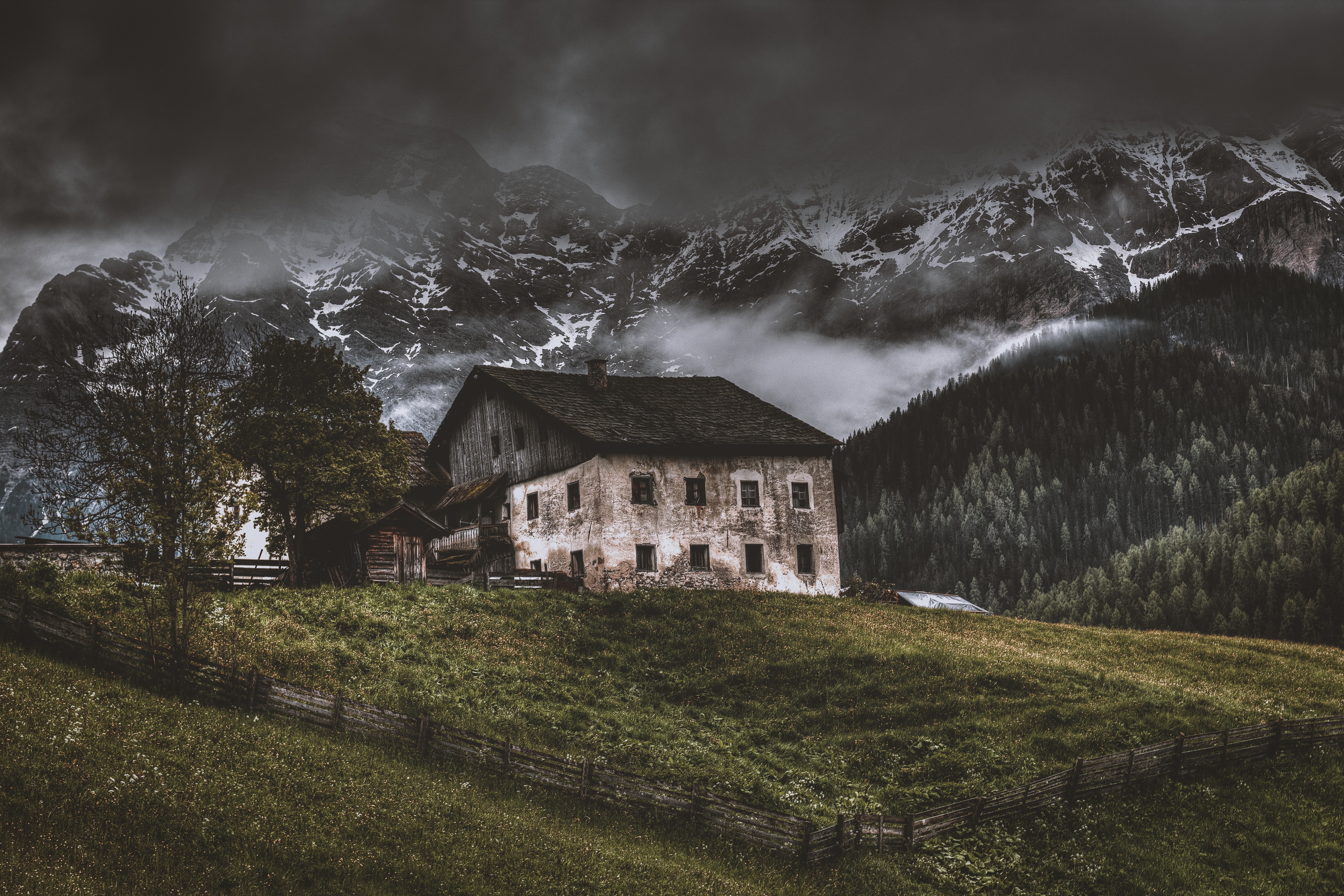 Old house on a grassy hill with mountains HD Wallpaper