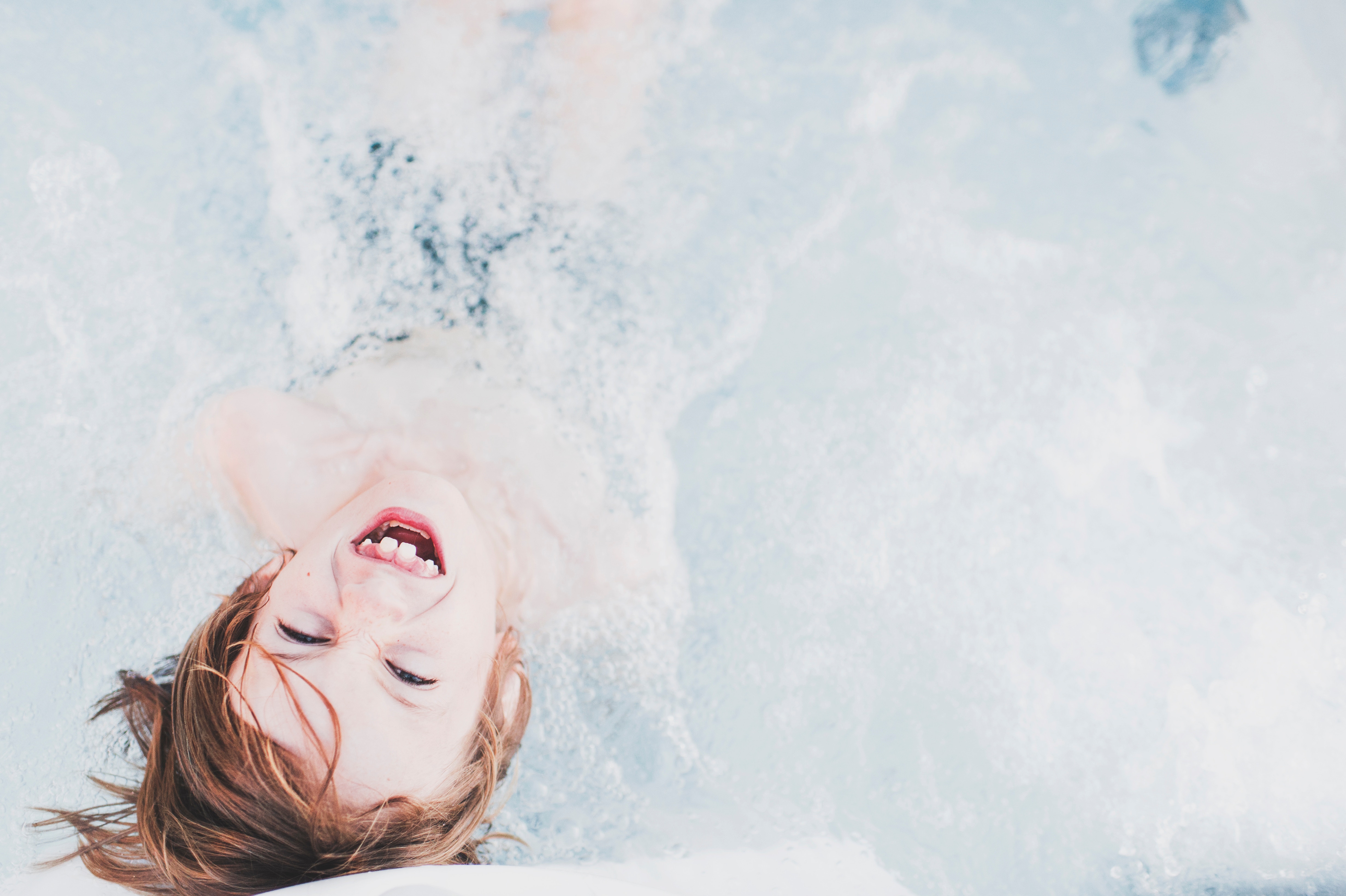 Child laughing in a bubbly pool HD Wallpaper