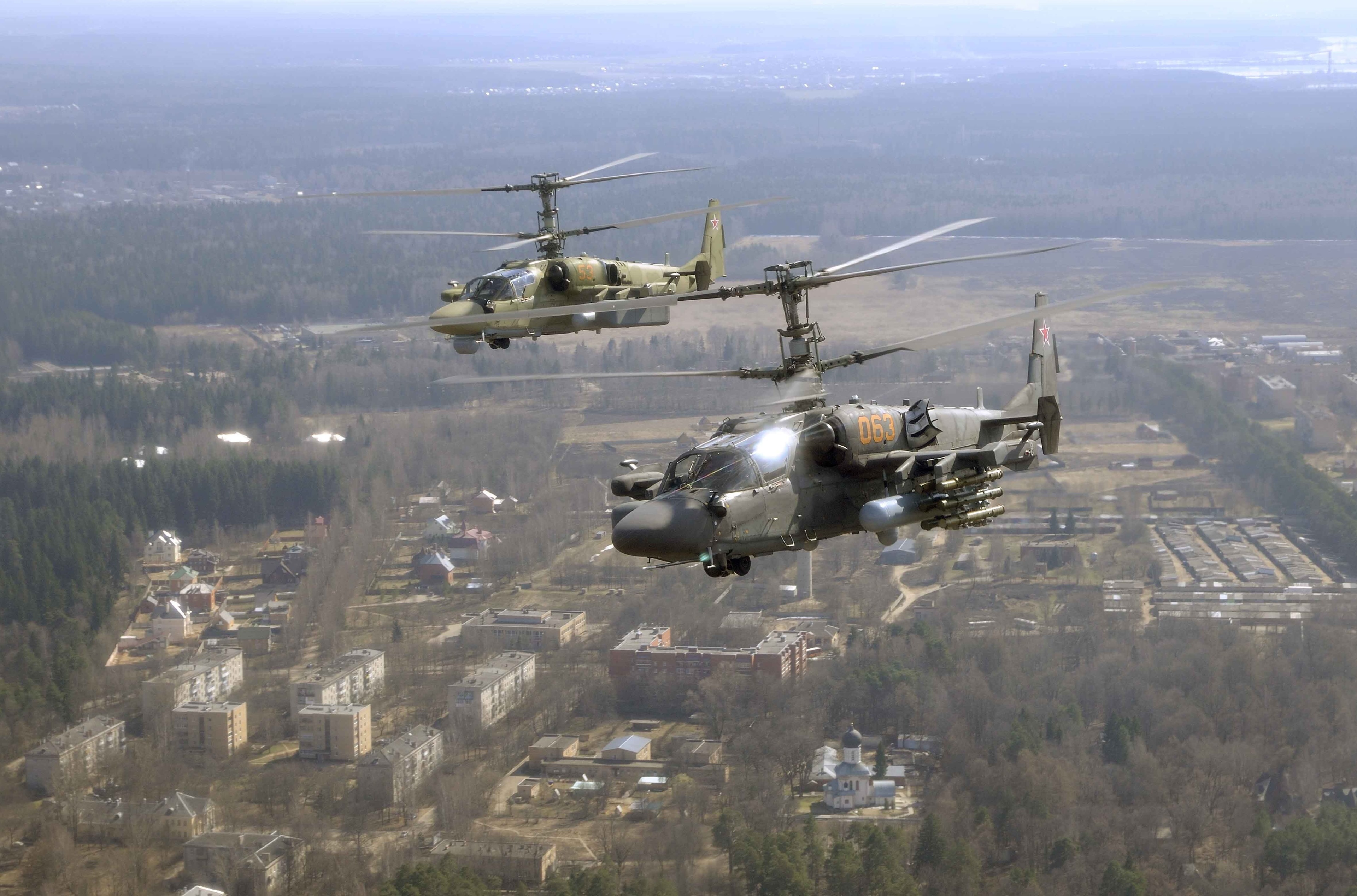 Kamov Ka-50 Black Shark helicopters flying over a town HD Wallpaper