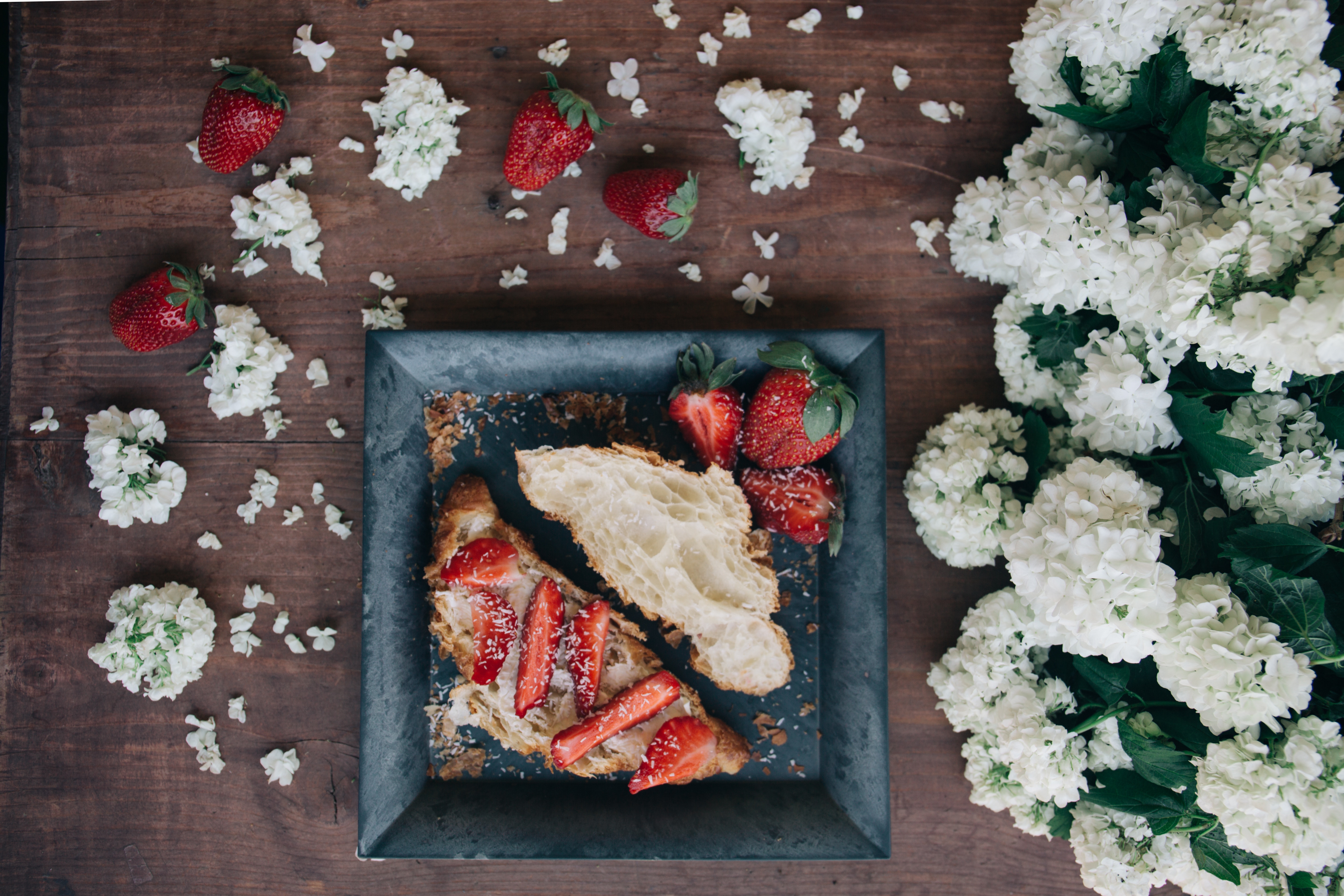 Croissant with strawberries and flowers on a wooden table HD Wallpaper