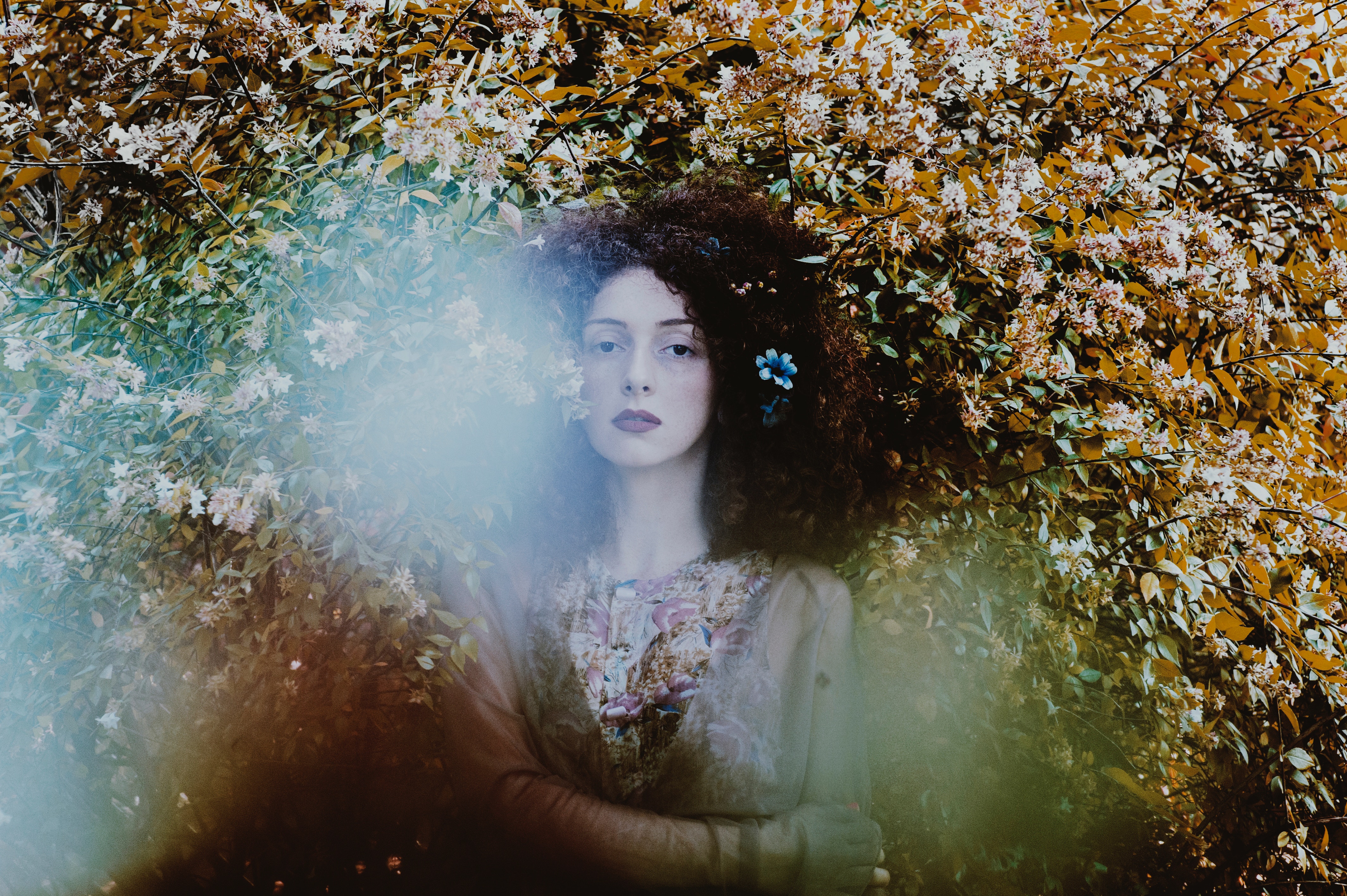Woman with curly hair and flowers in a garden HD Wallpaper