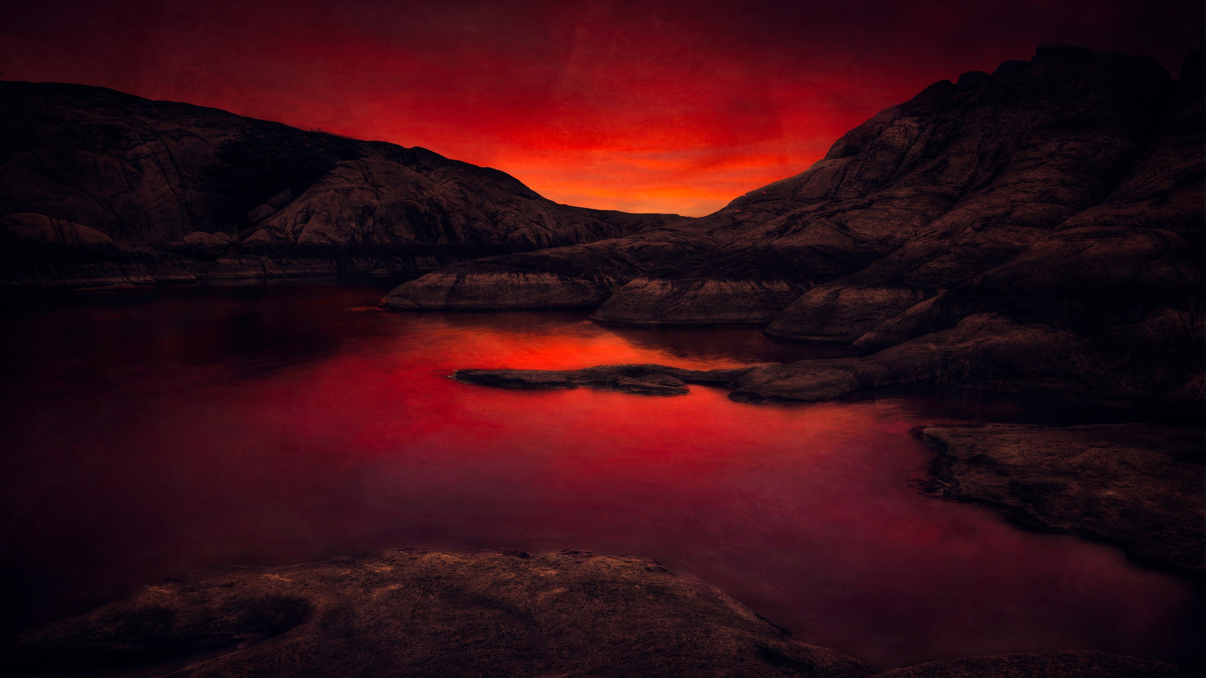 Dark rocky landscape with red sunset over water 4K HD Wallpaper