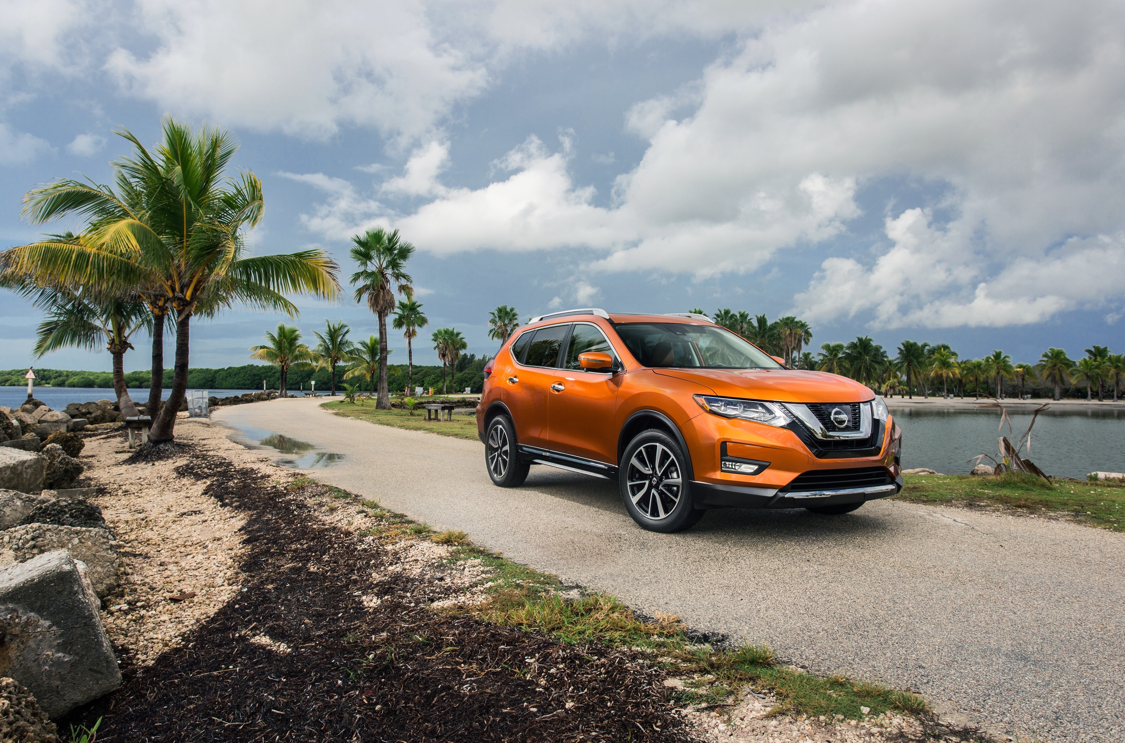 Orange Nissan Rogue SL on a coastal road HD Wallpaper