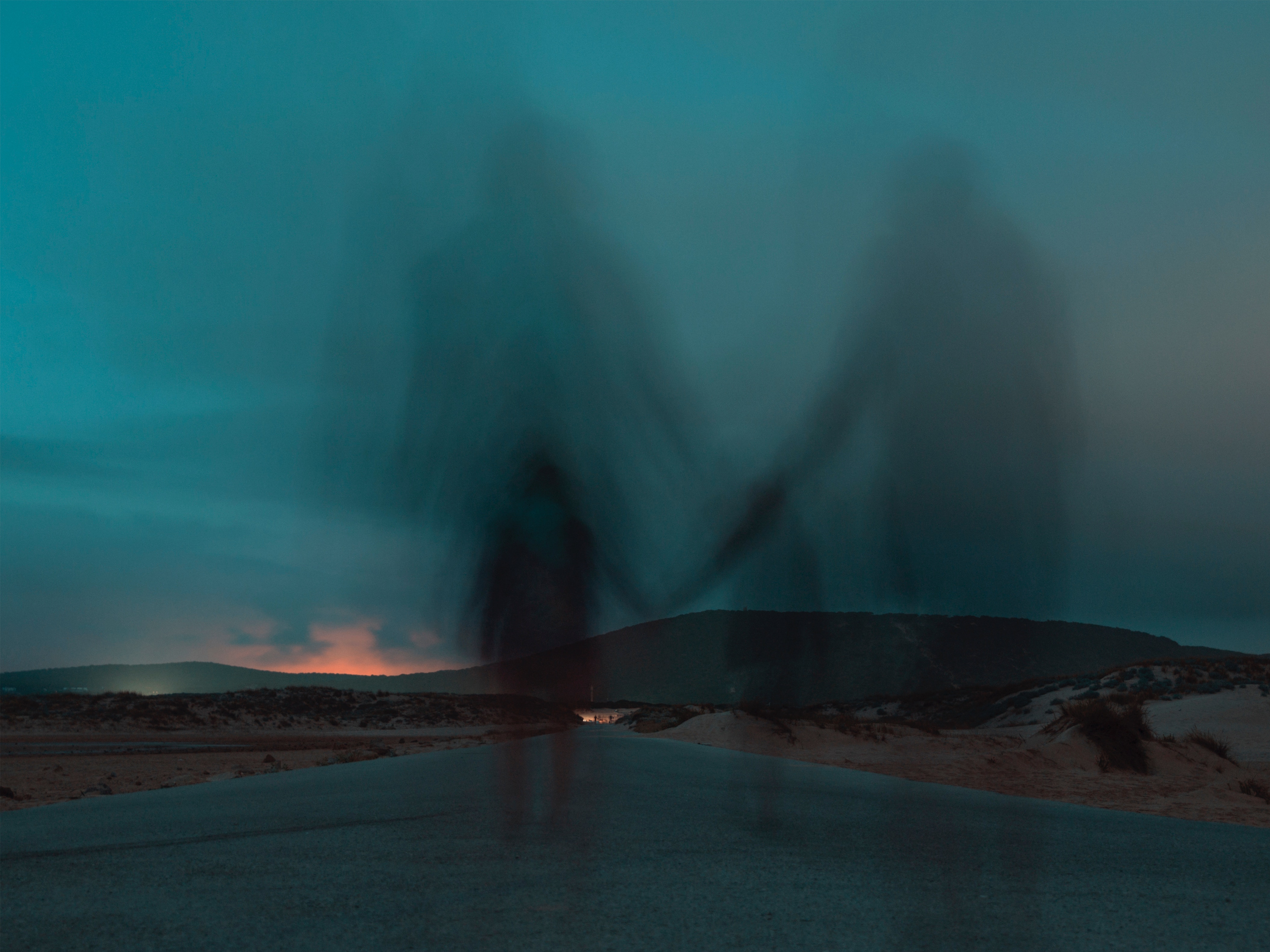 Two blurred figures holding hands on a road at dusk HD Wallpaper