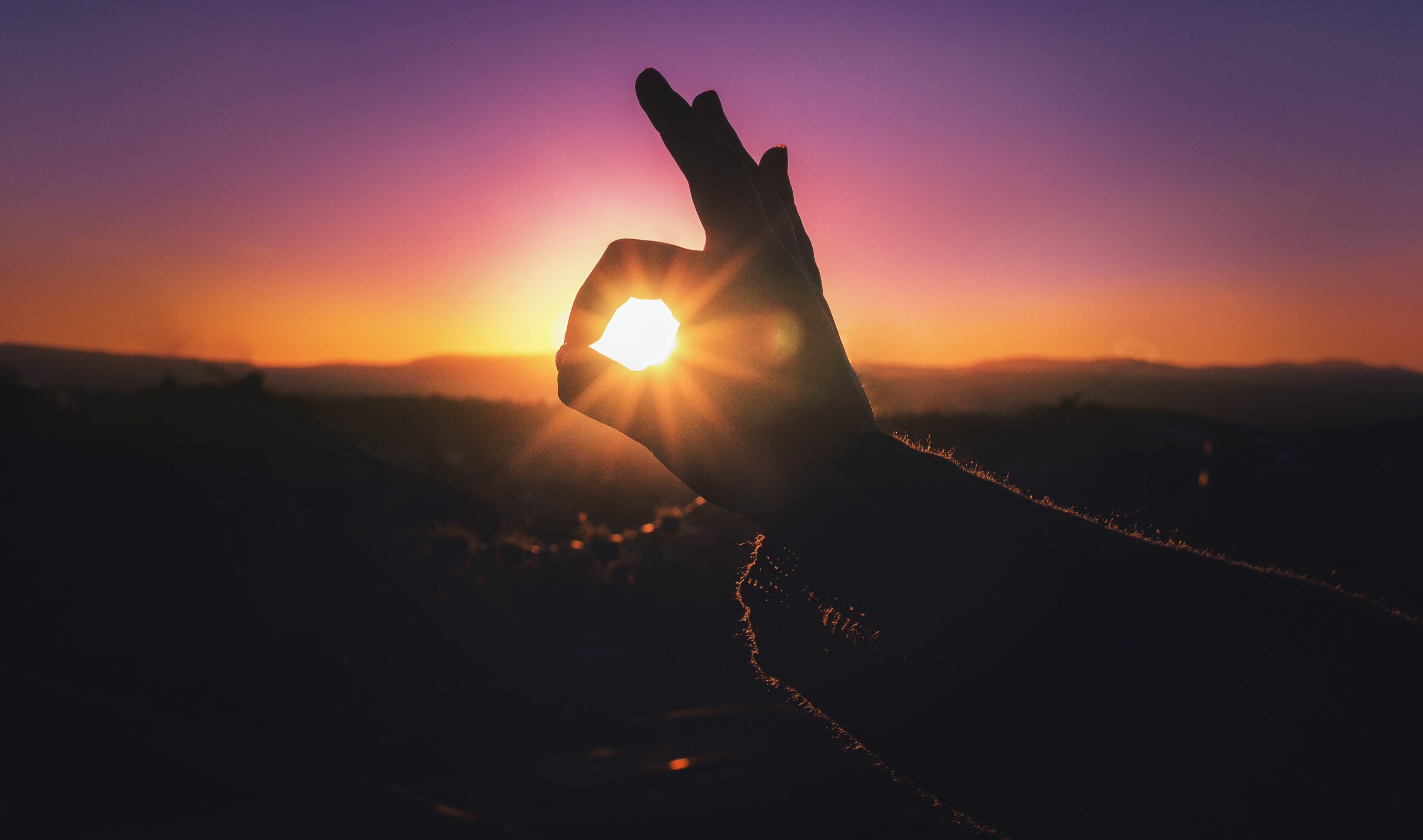 Silhouette of a hand making an OK sign at sunset HD Wallpaper