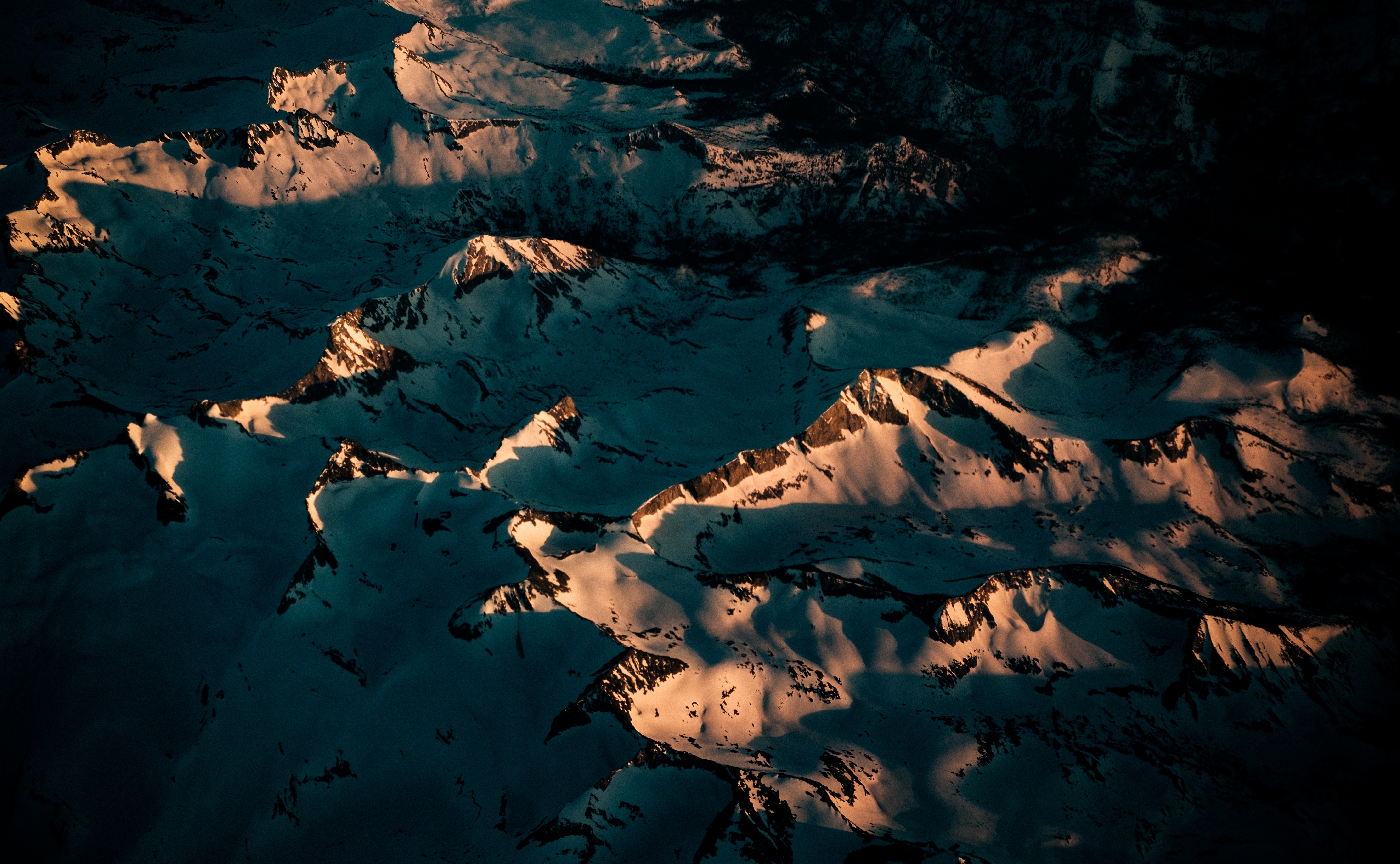 Aerial view of snow-covered mountains at sunset HD Wallpaper