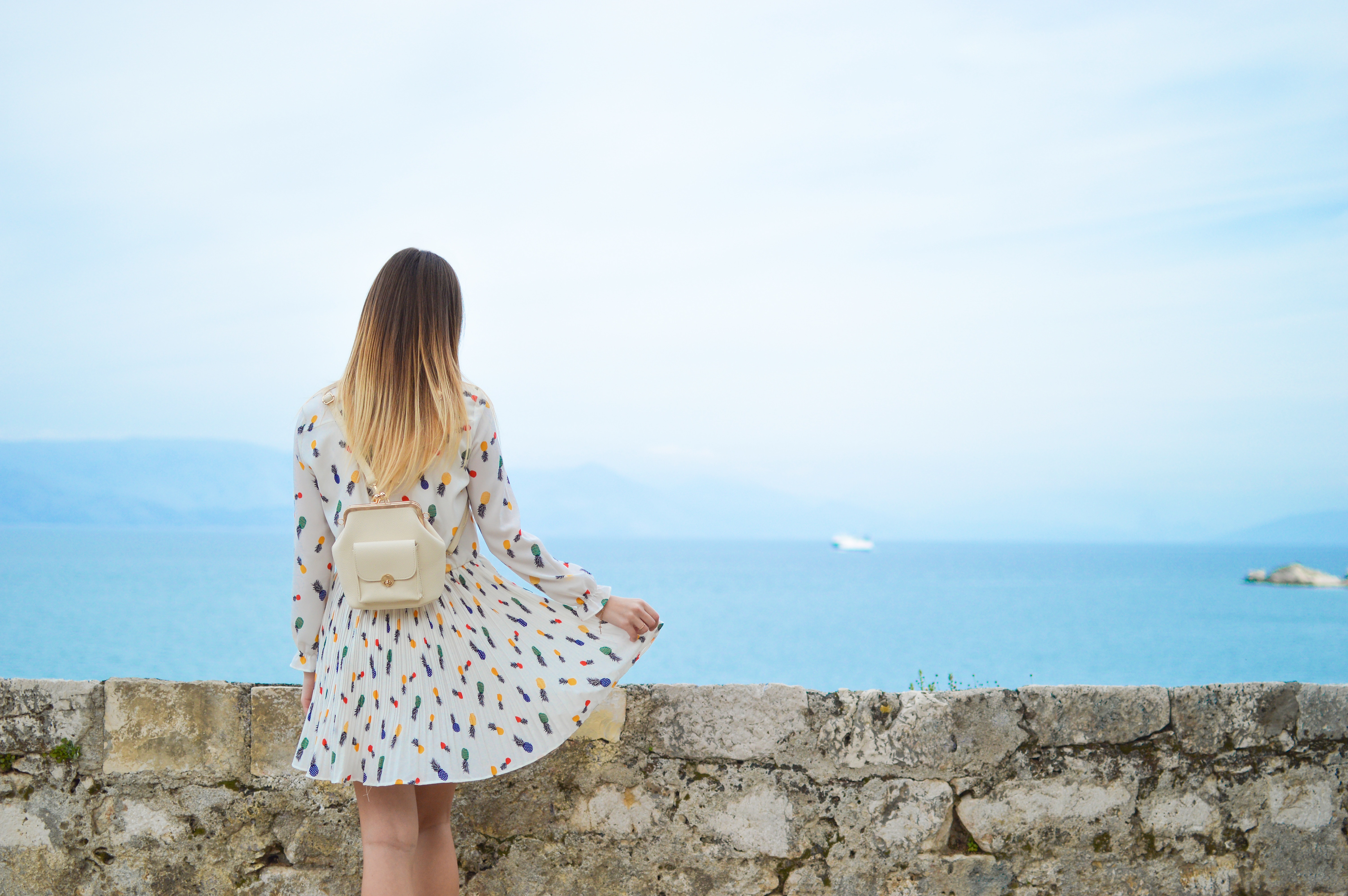 Woman in patterned dress with backpack overlooking the sea in Corfu HD Wallpaper