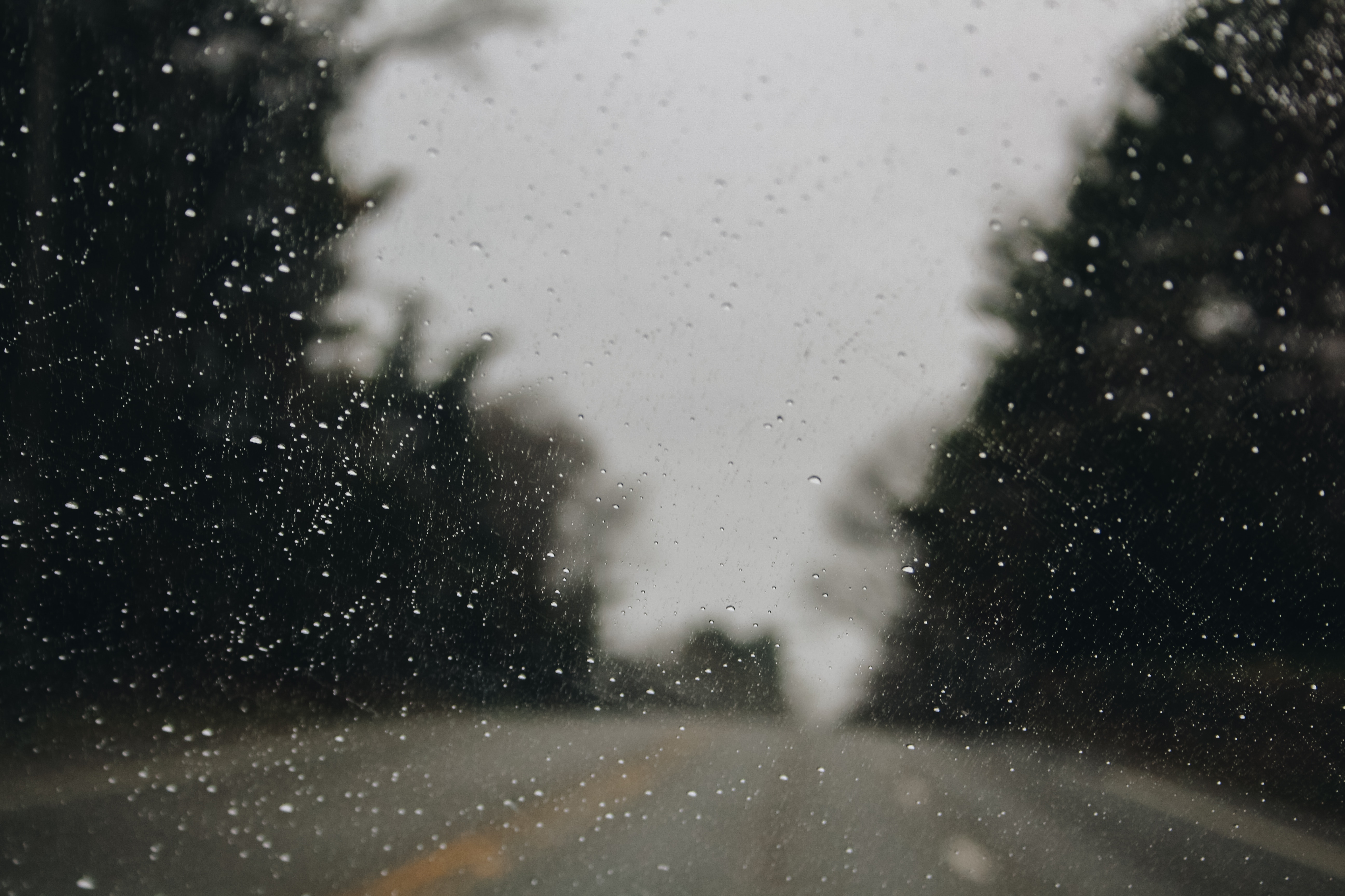 Raindrops on a car window looking out at a road HD Wallpaper