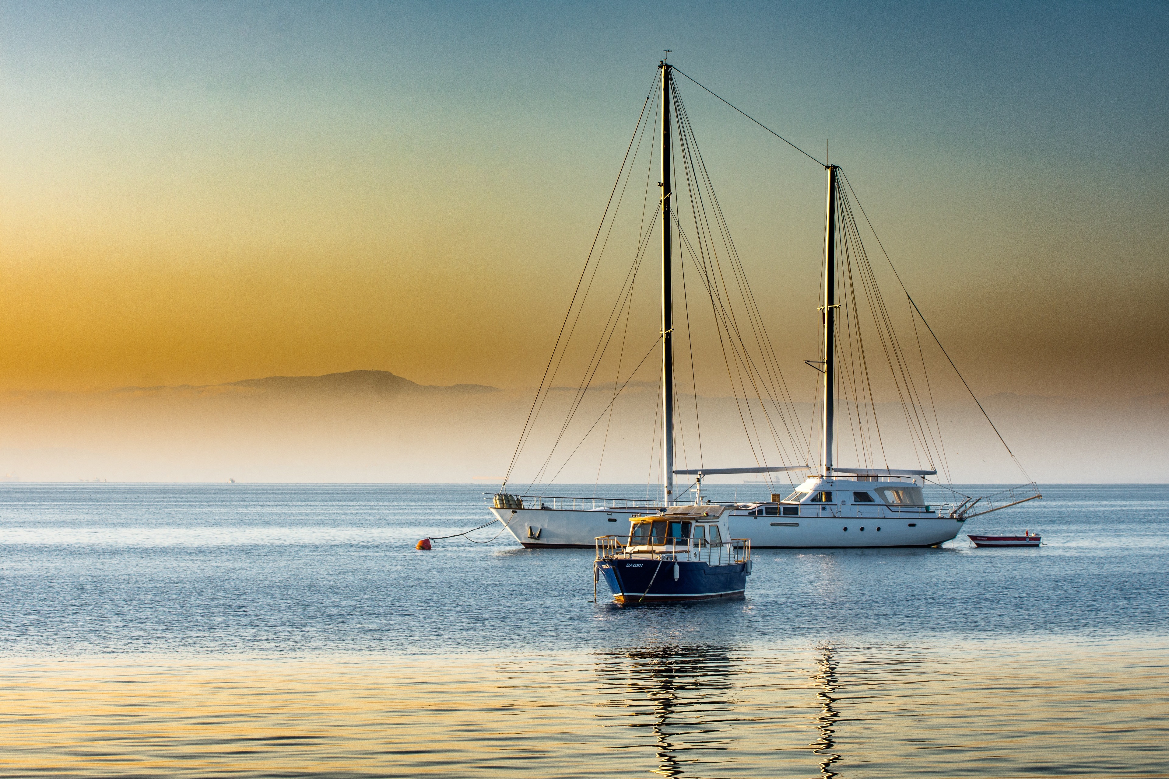 Two yachts and a small boat on the water at sunset HD Wallpaper