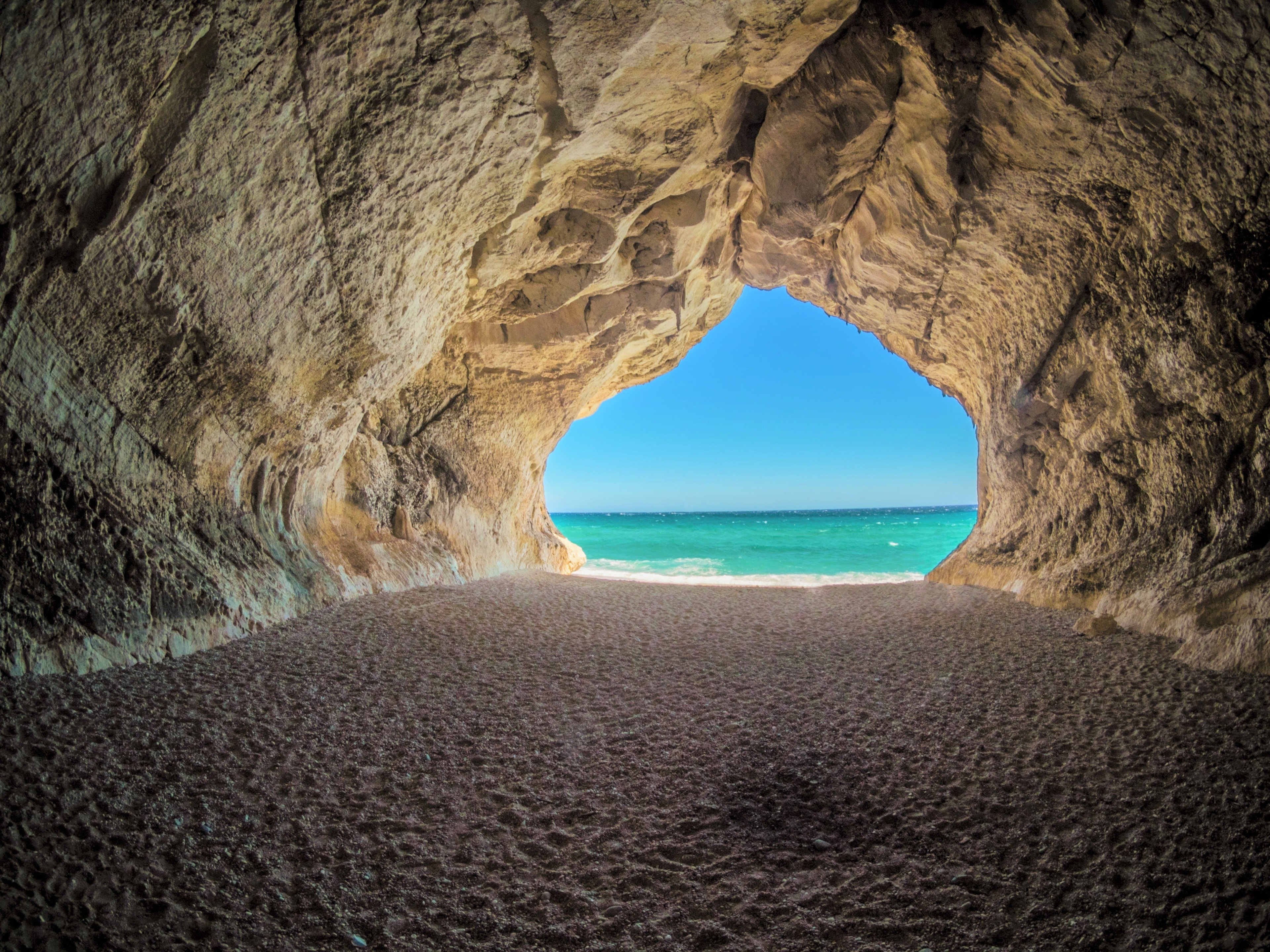 Cave entrance to a beach with turquoise water HD Wallpaper