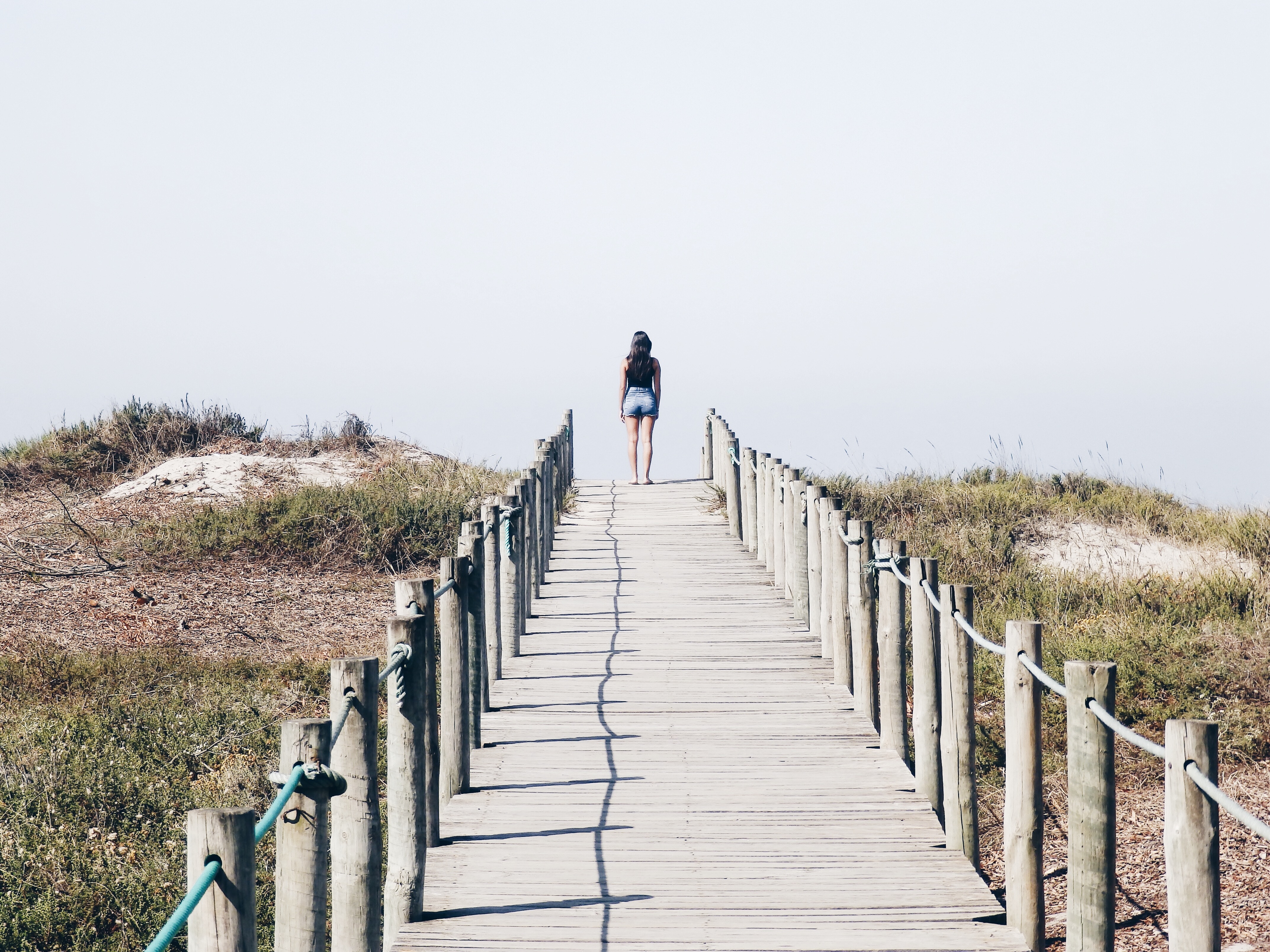 Woman walking on a wooden path by the beach HD Wallpaper