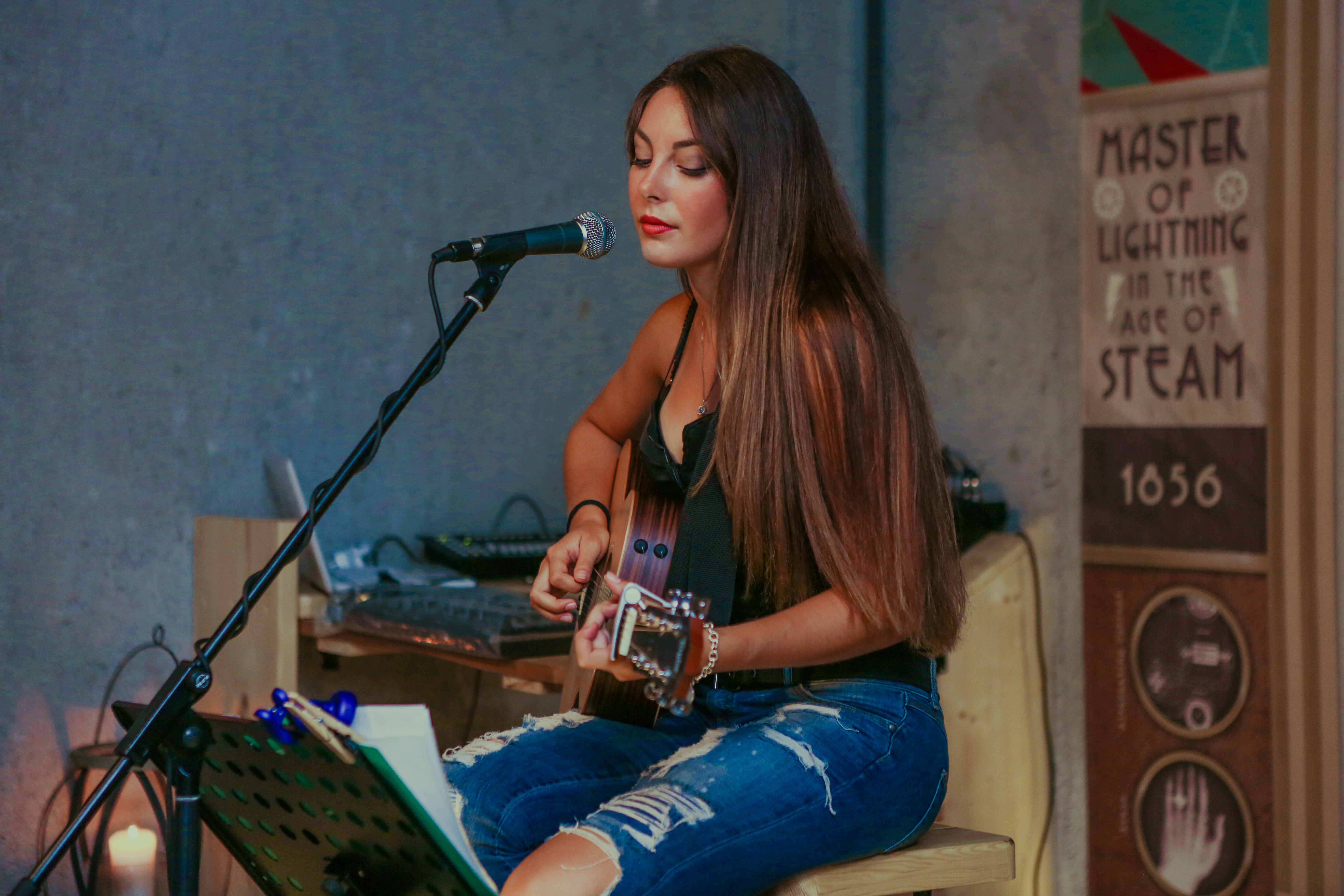Woman playing acoustic guitar and singing into a microphone HD Wallpaper