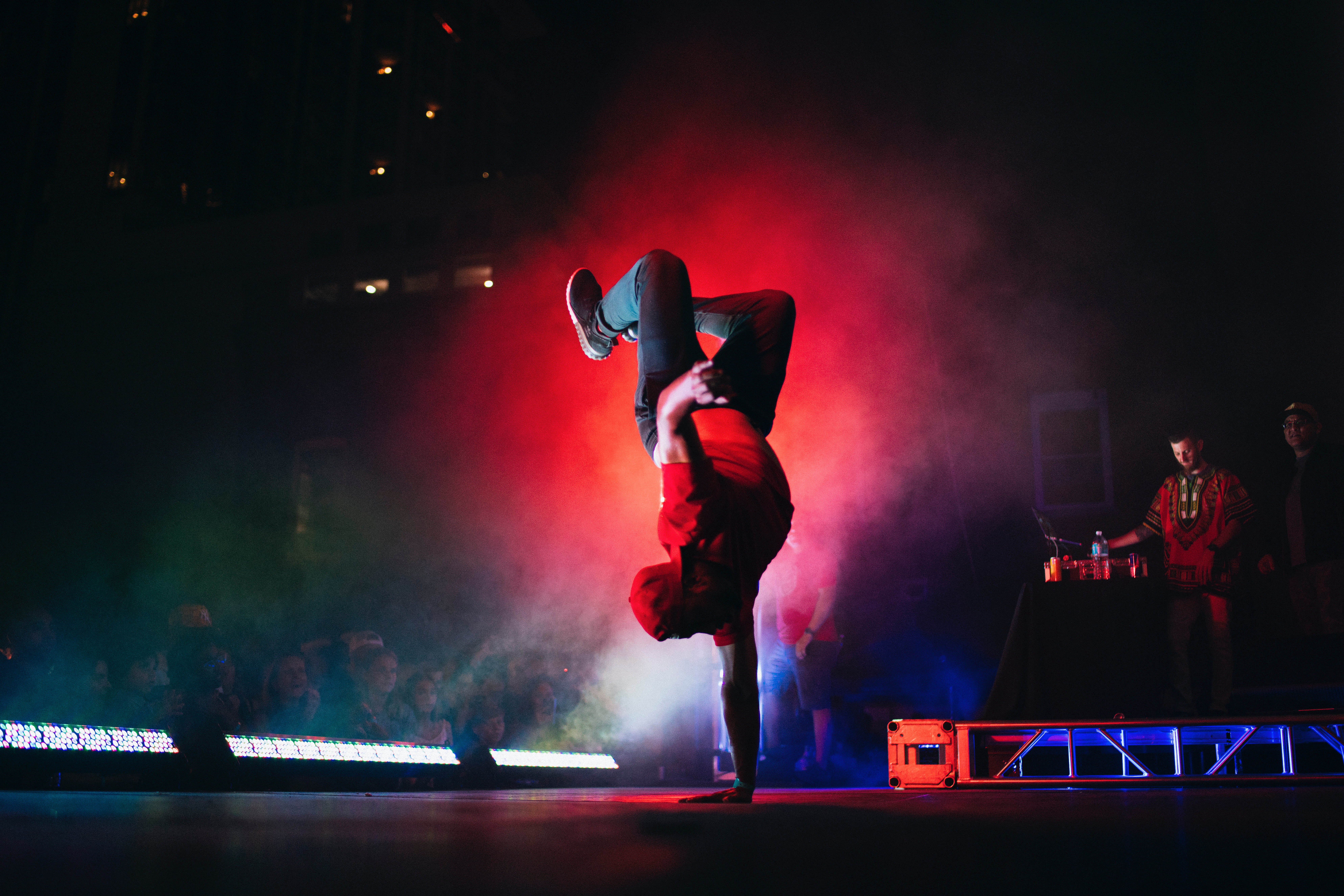 Breakdancer performs a handstand on stage with red lighting HD Wallpaper