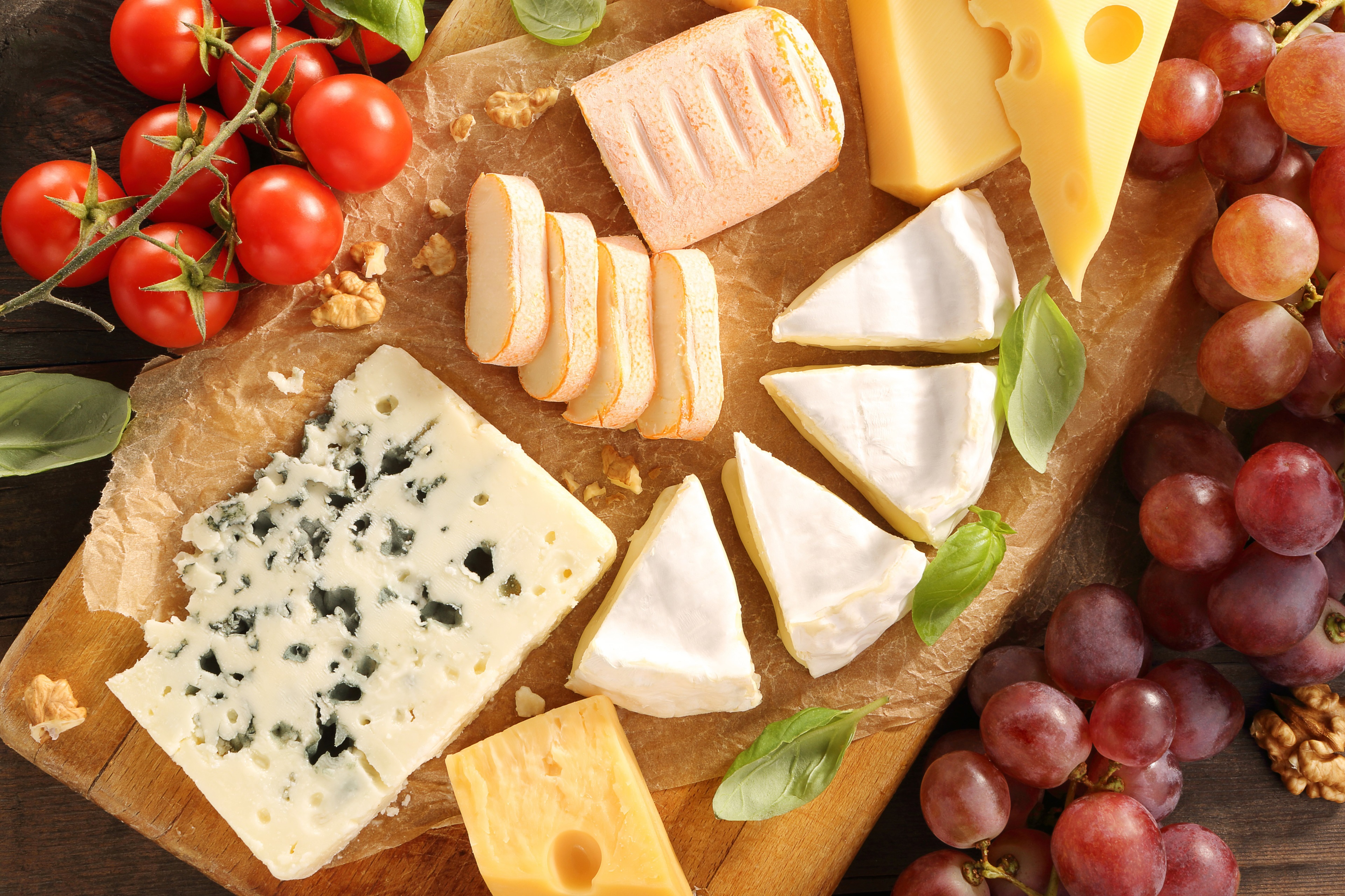 Cheese board with tomatoes, grapes, and walnuts HD Wallpaper