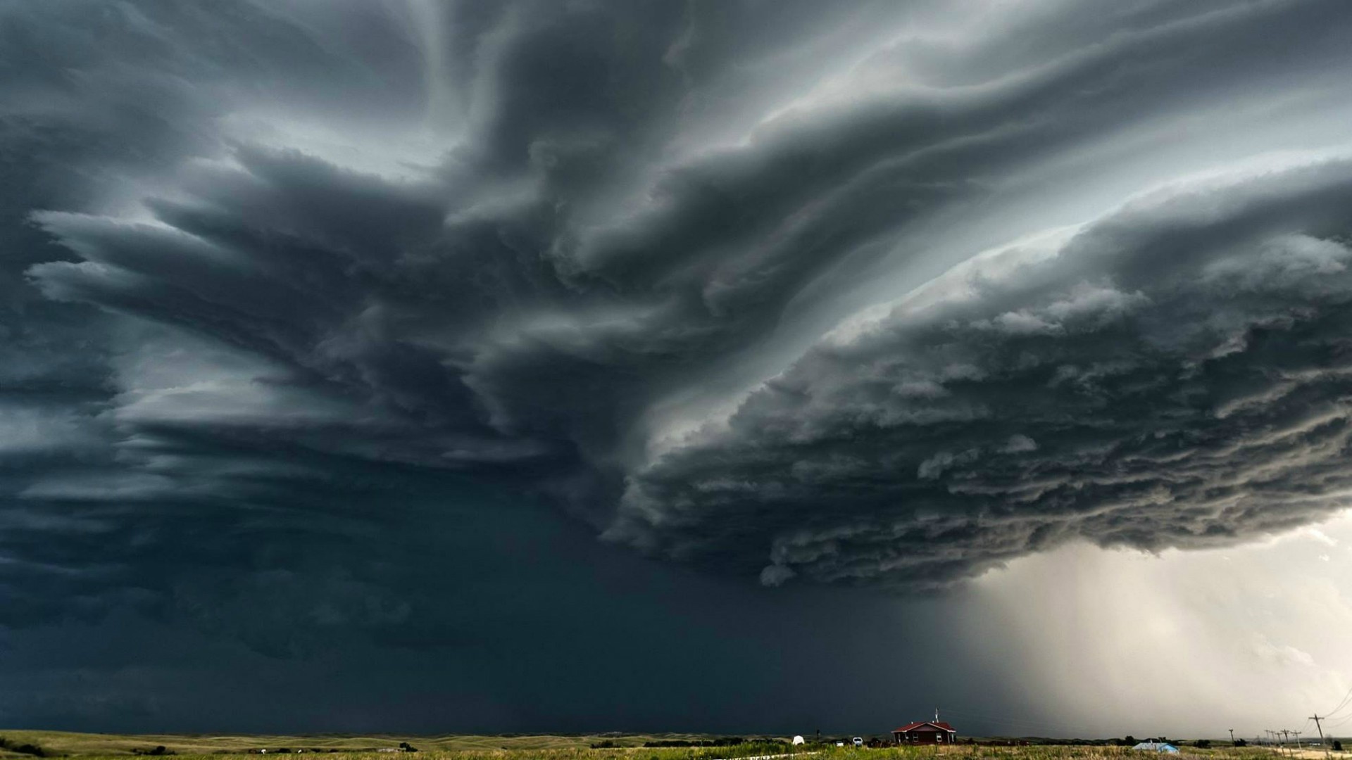 Storm clouds over a rural landscape with a house HD Wallpaper