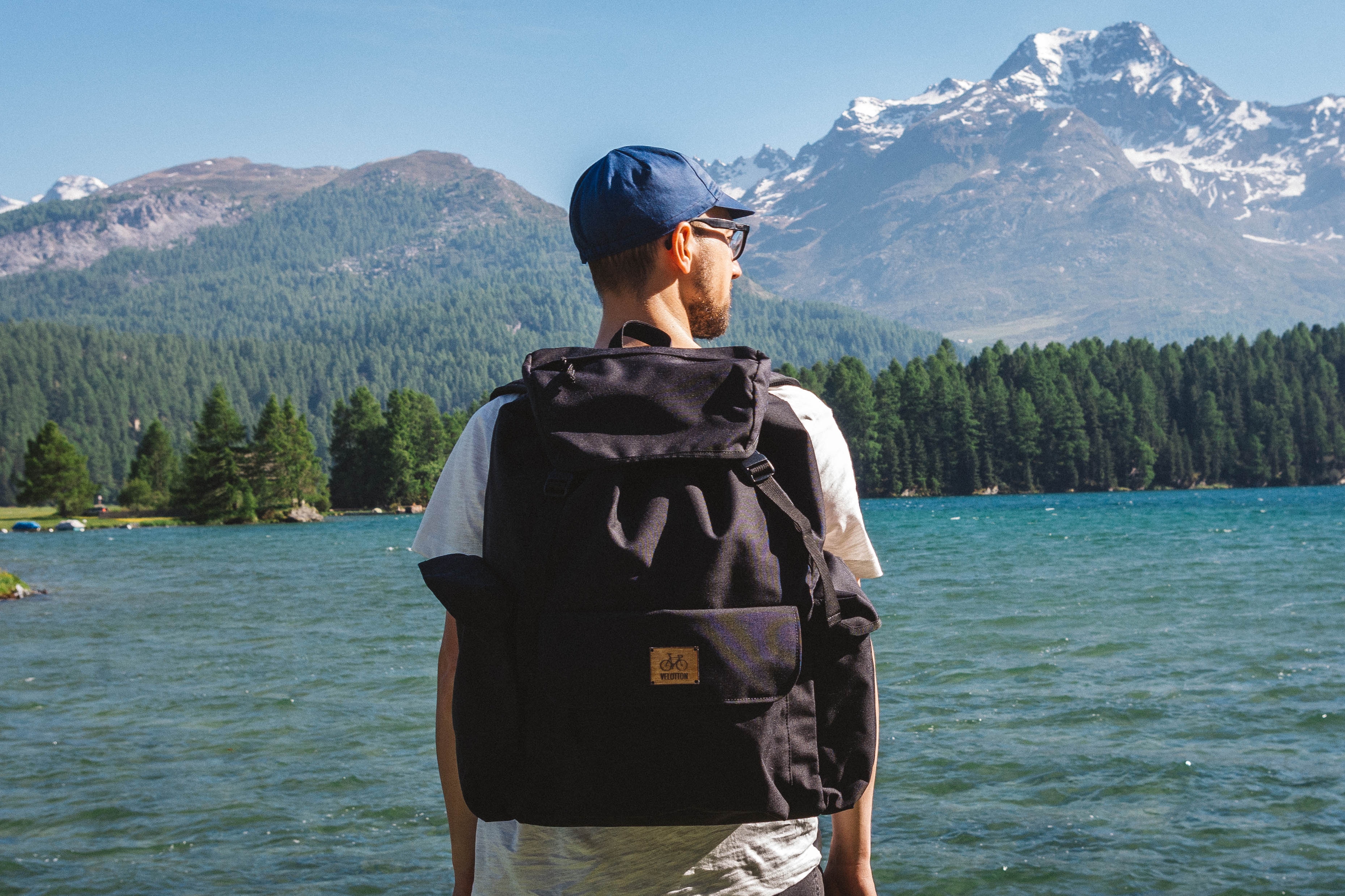Man with backpack by a mountain lake in St. Moritz HD Wallpaper