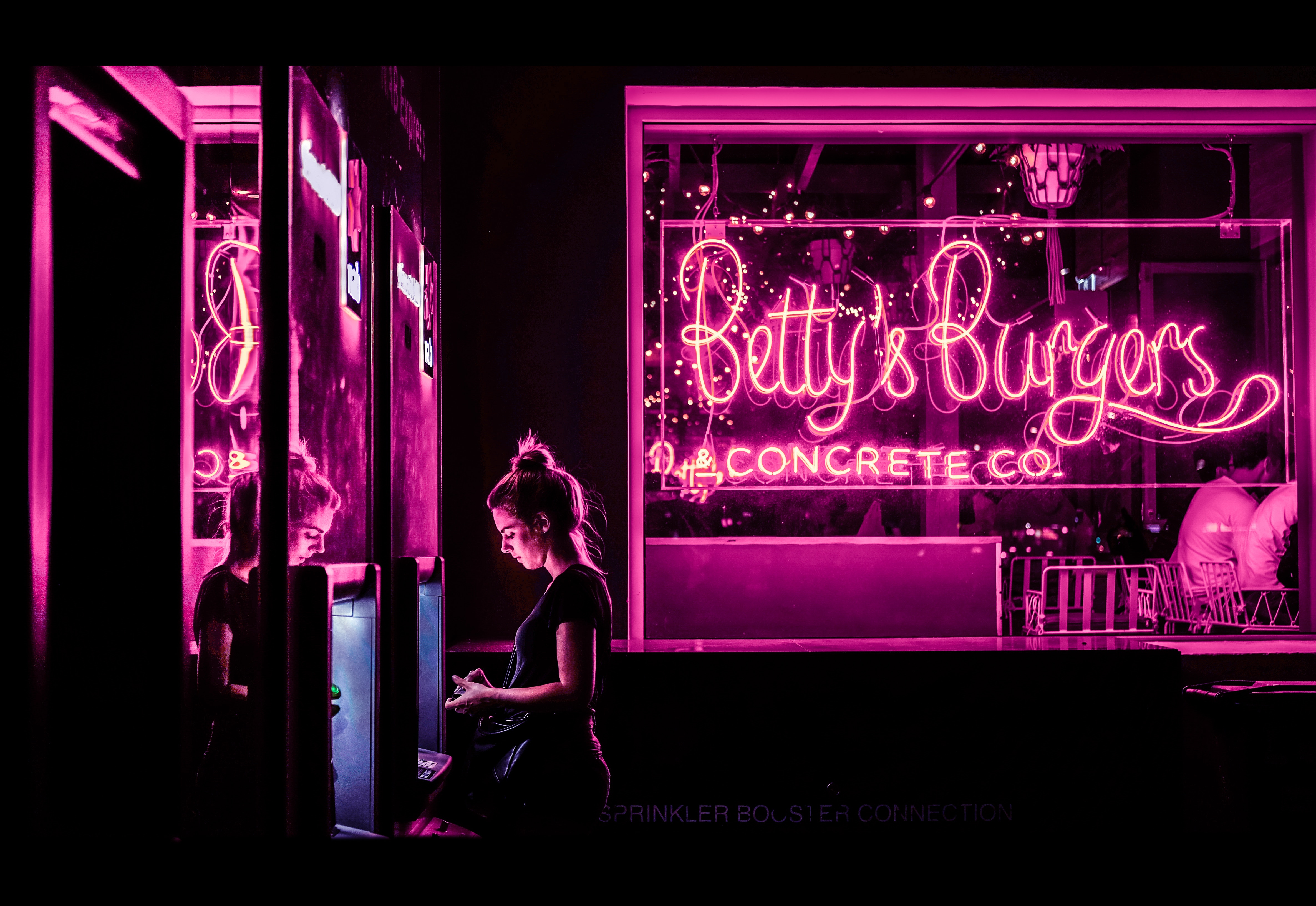 Betty's Burgers neon sign with woman at ATM HD Wallpaper