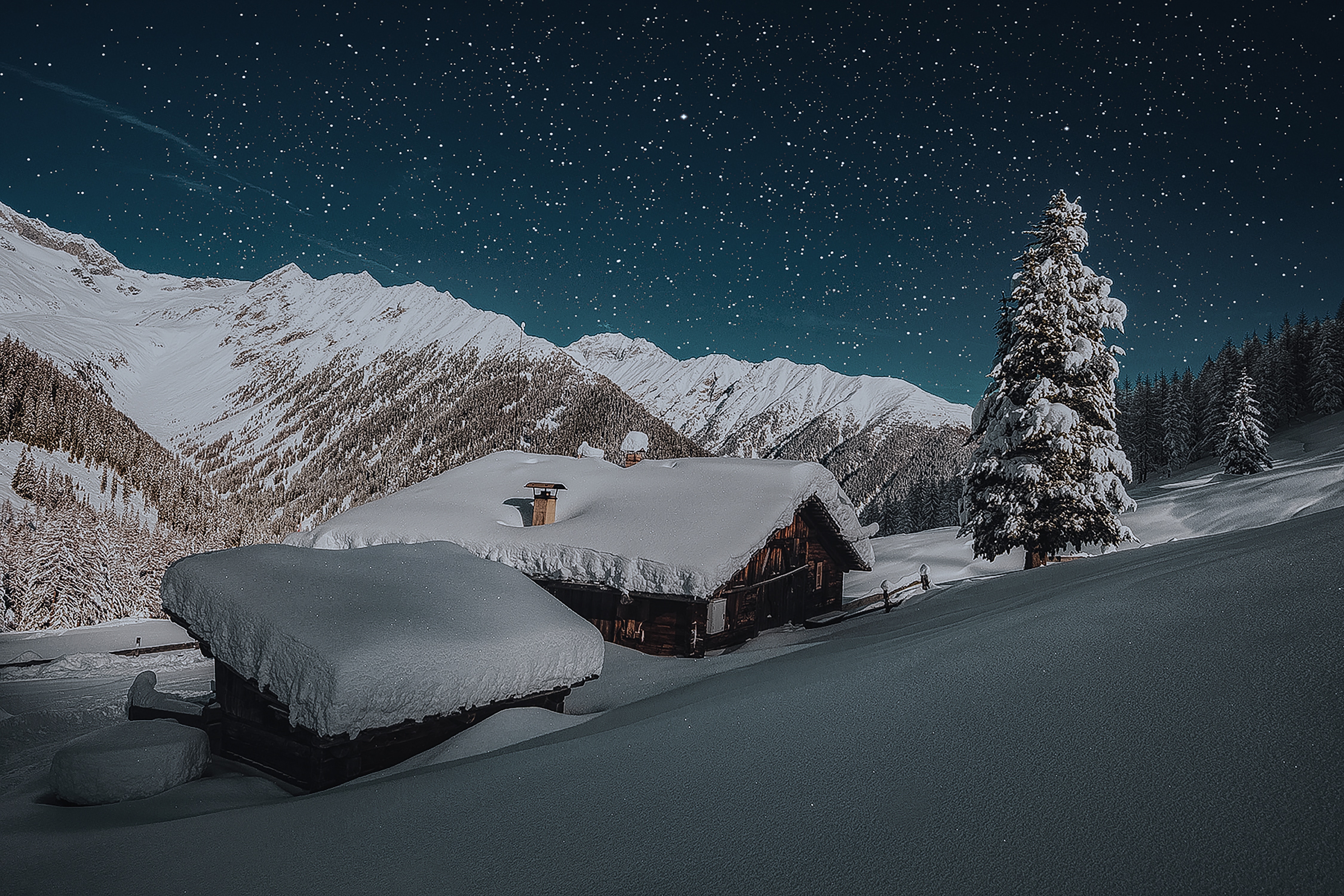 Snowy cabin in mountains under starry night sky HD Wallpaper