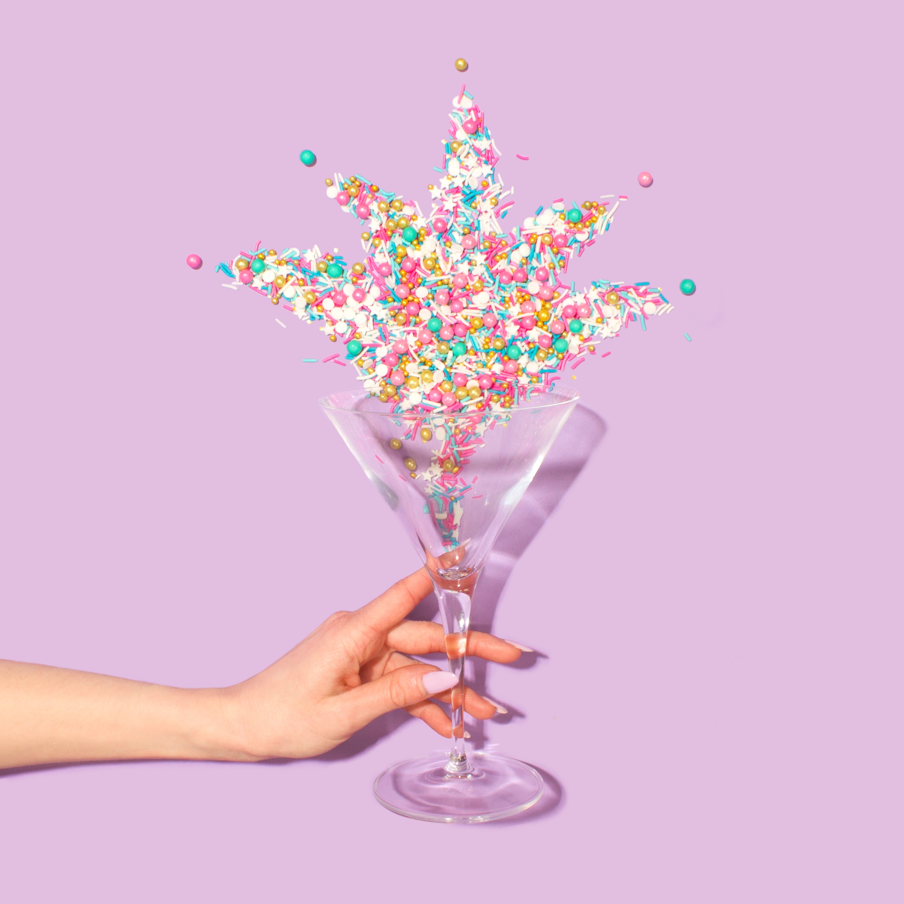 Hand holding martini glass with colorful sprinkles HD Wallpaper