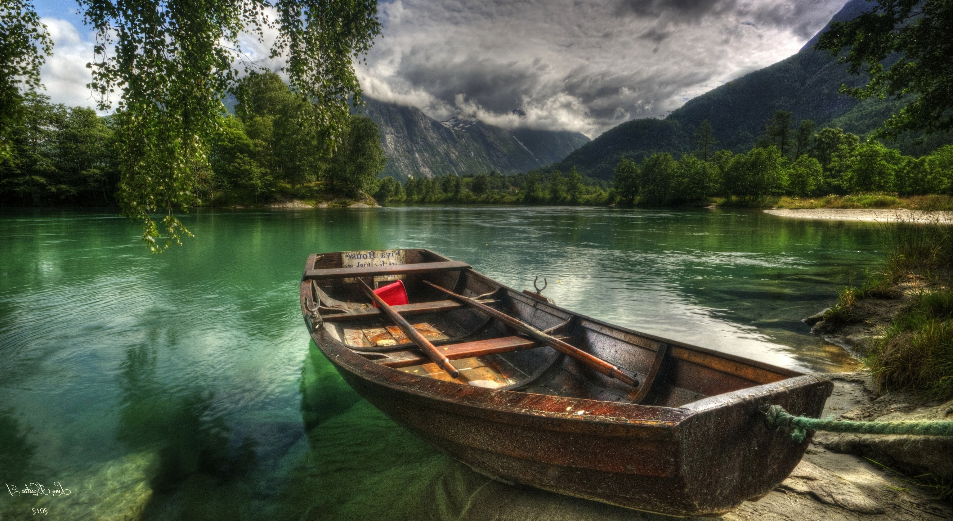 Rowboat on a clear river with mountains in the background HD Wallpaper