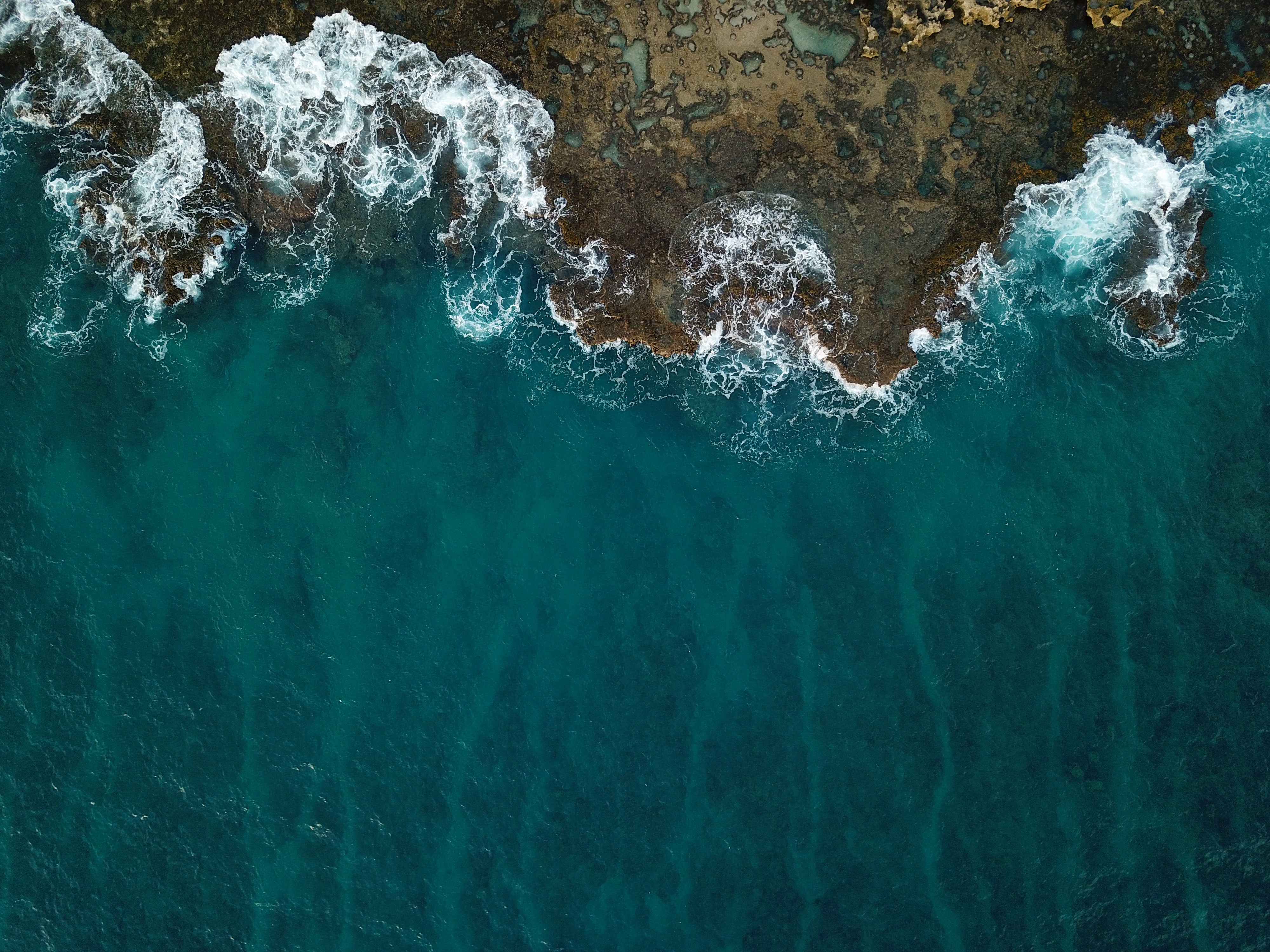 Aerial view of ocean waves crashing on a coral reef HD Wallpaper
