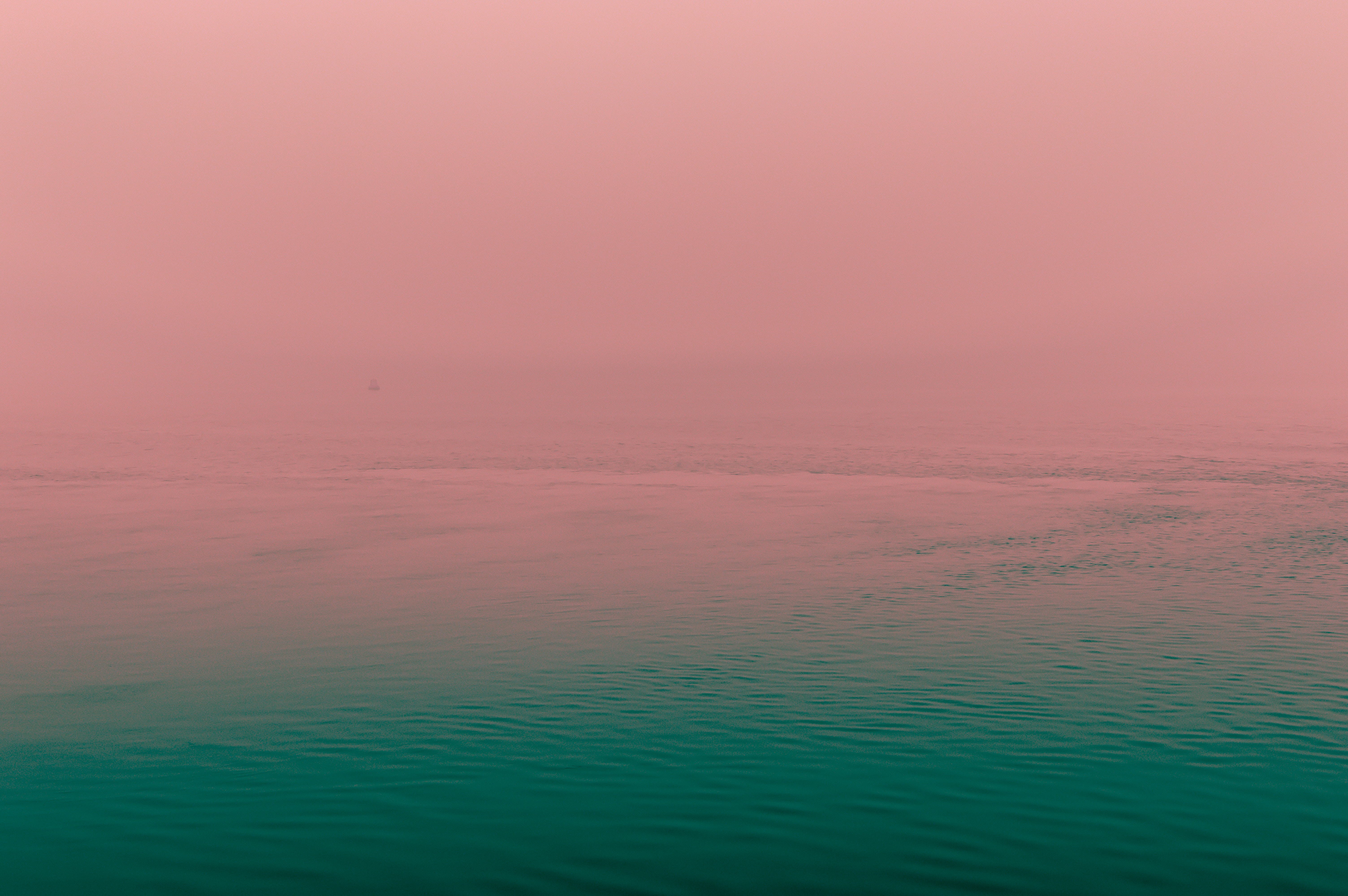 Pink fog over a calm green ocean with a distant sail HD Wallpaper