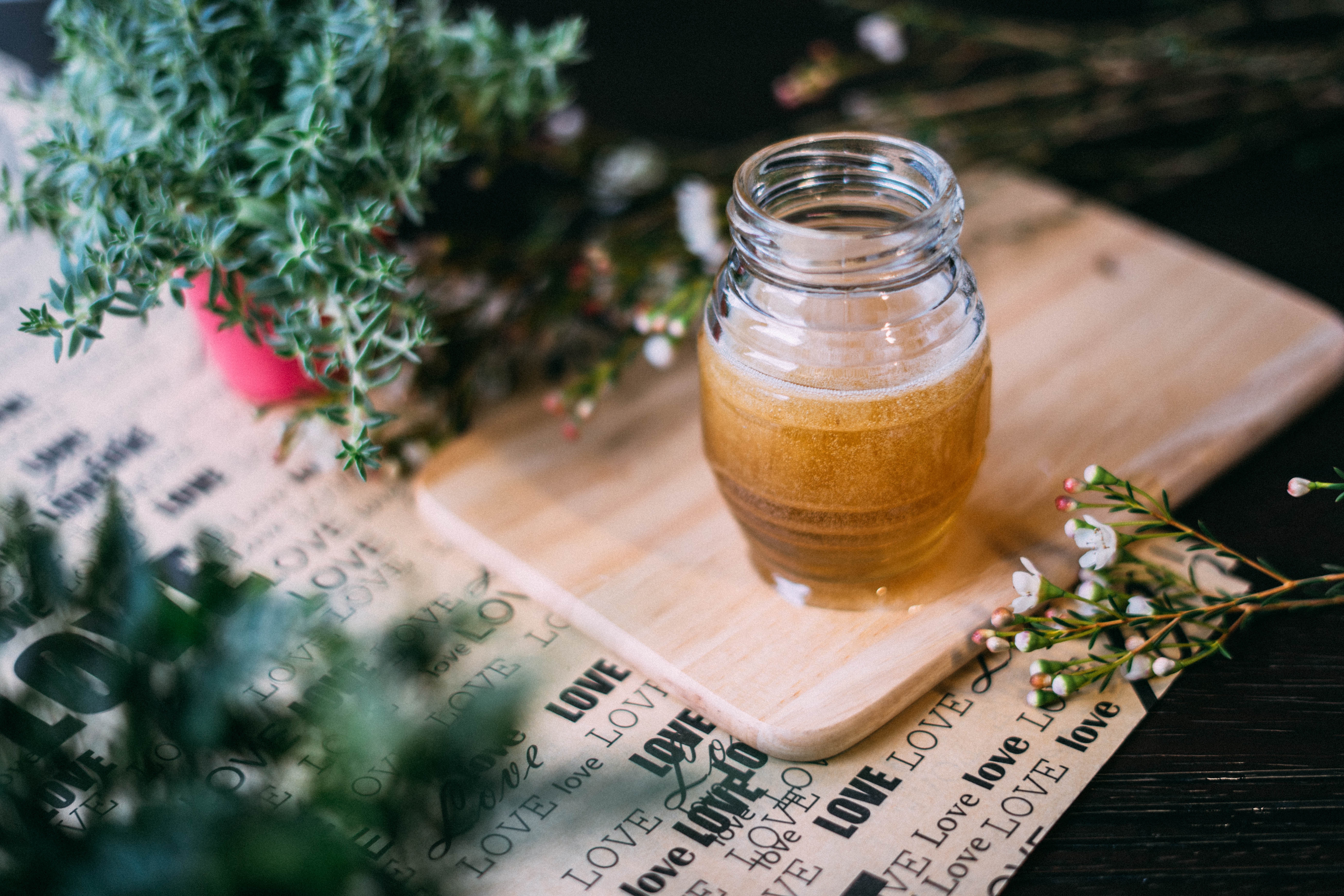 Jar of honey on a wooden board with plants HD Wallpaper