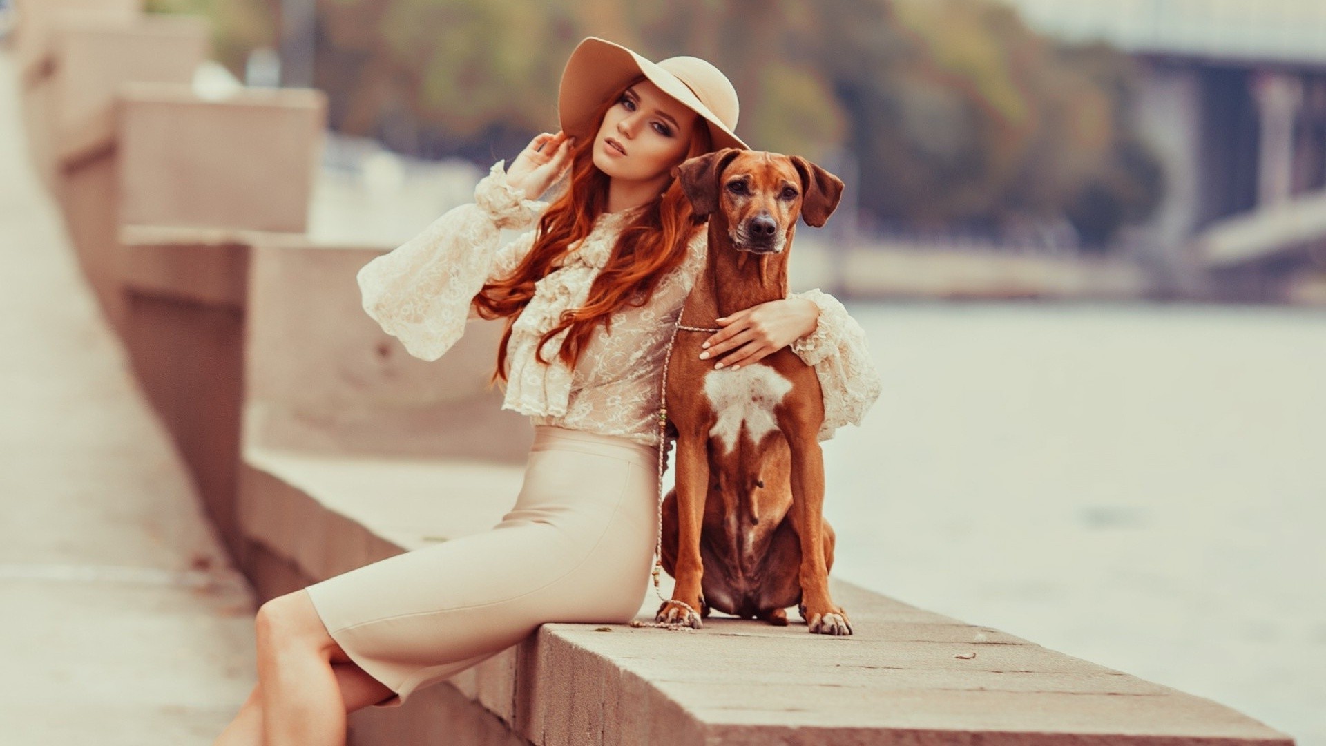 Woman in hat with dog sitting by water HD Wallpaper