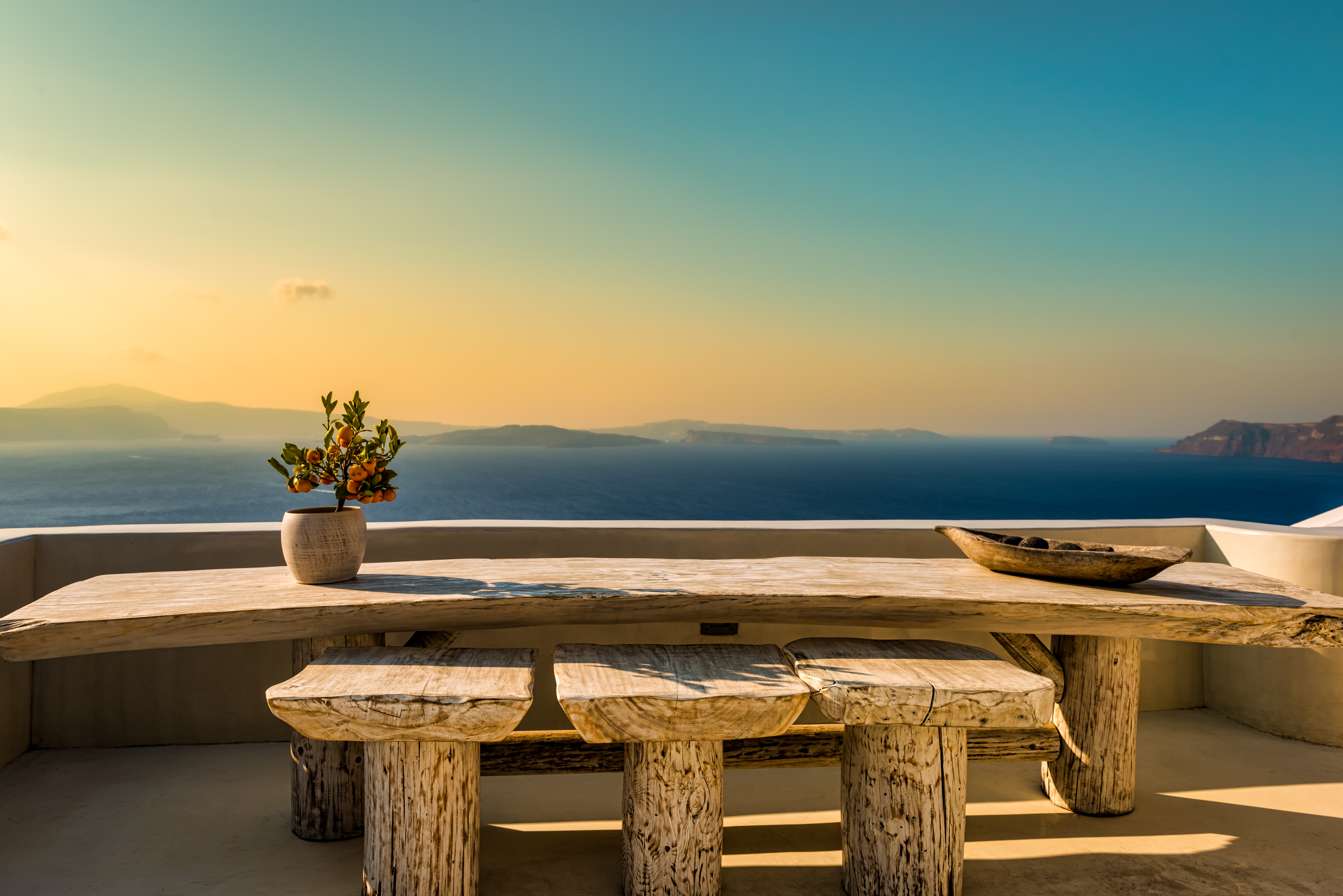 Wooden table and stools on a rooftop overlooking the sea at sunrise HD Wallpaper