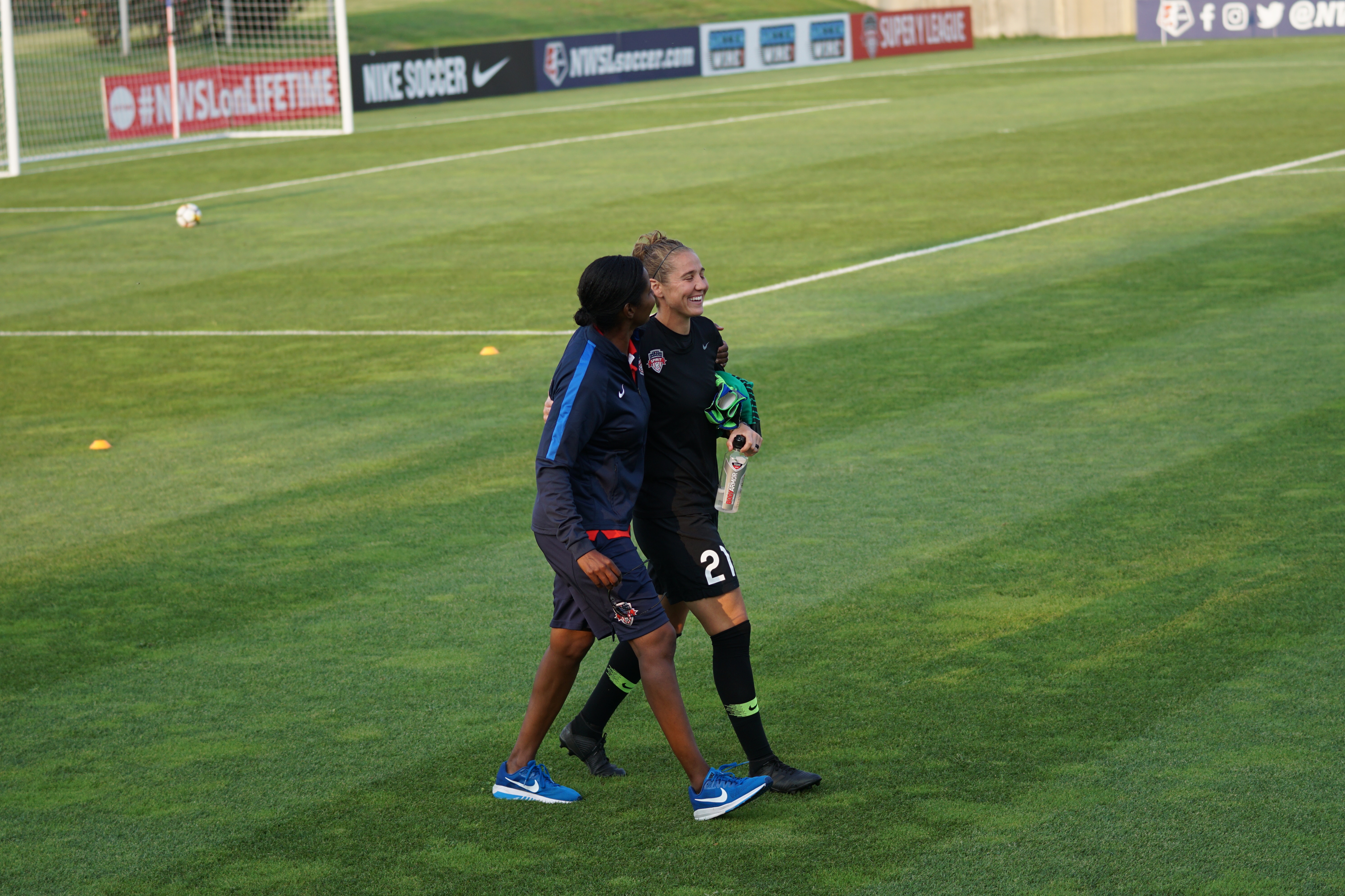 Two women walking on a soccer field HD Wallpaper