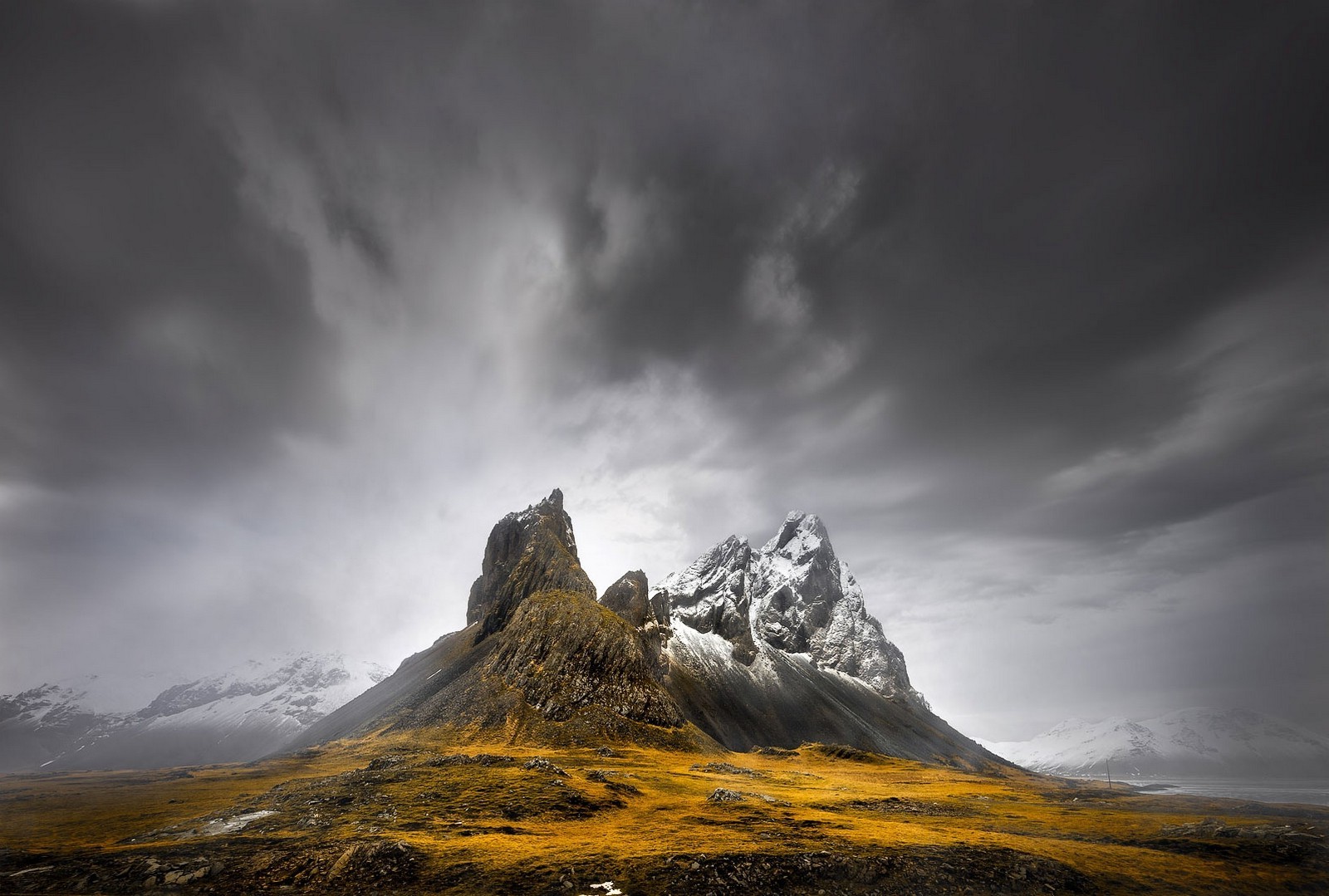 Snowy mountain peak under dark clouds in Iceland HD Wallpaper