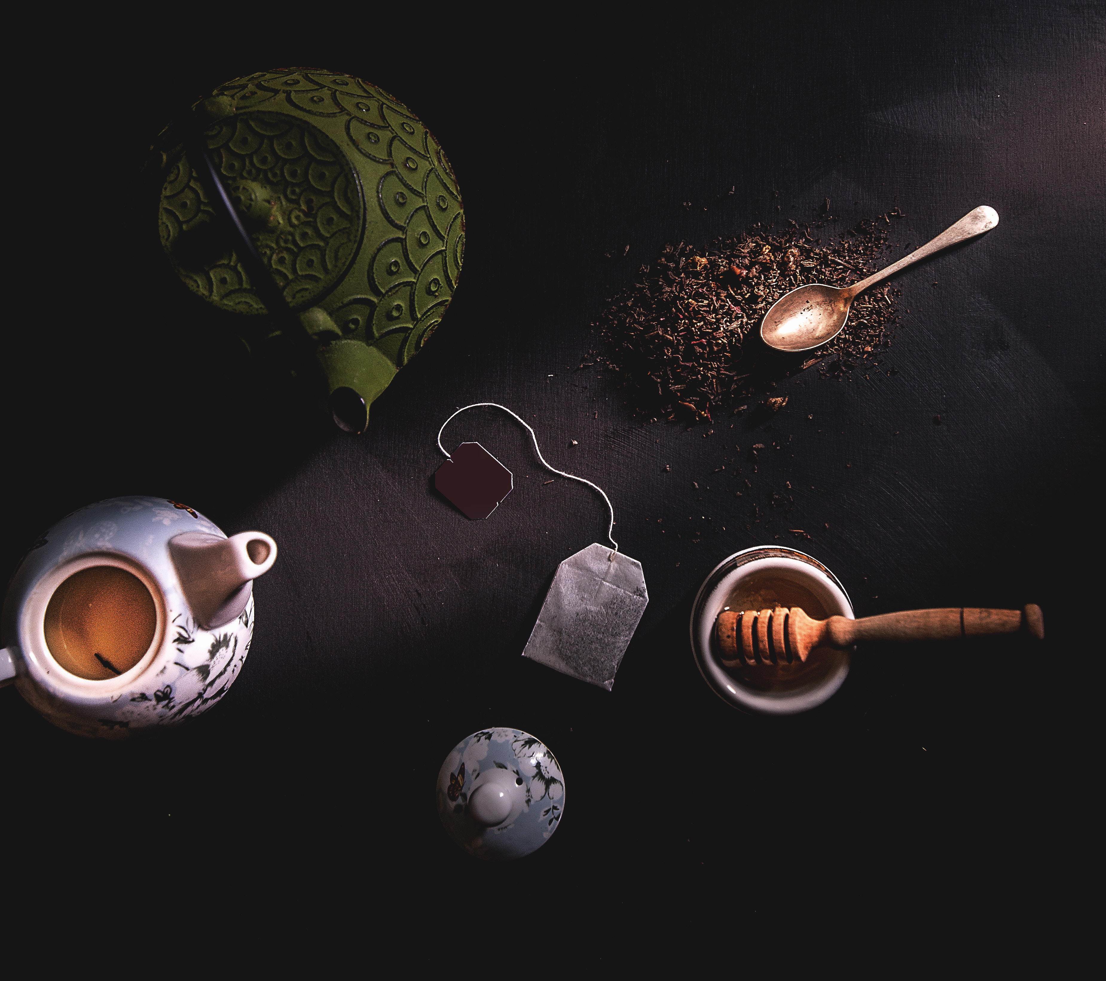 Flatlay of tea, teapot, spoon, and honey on a dark table HD Wallpaper