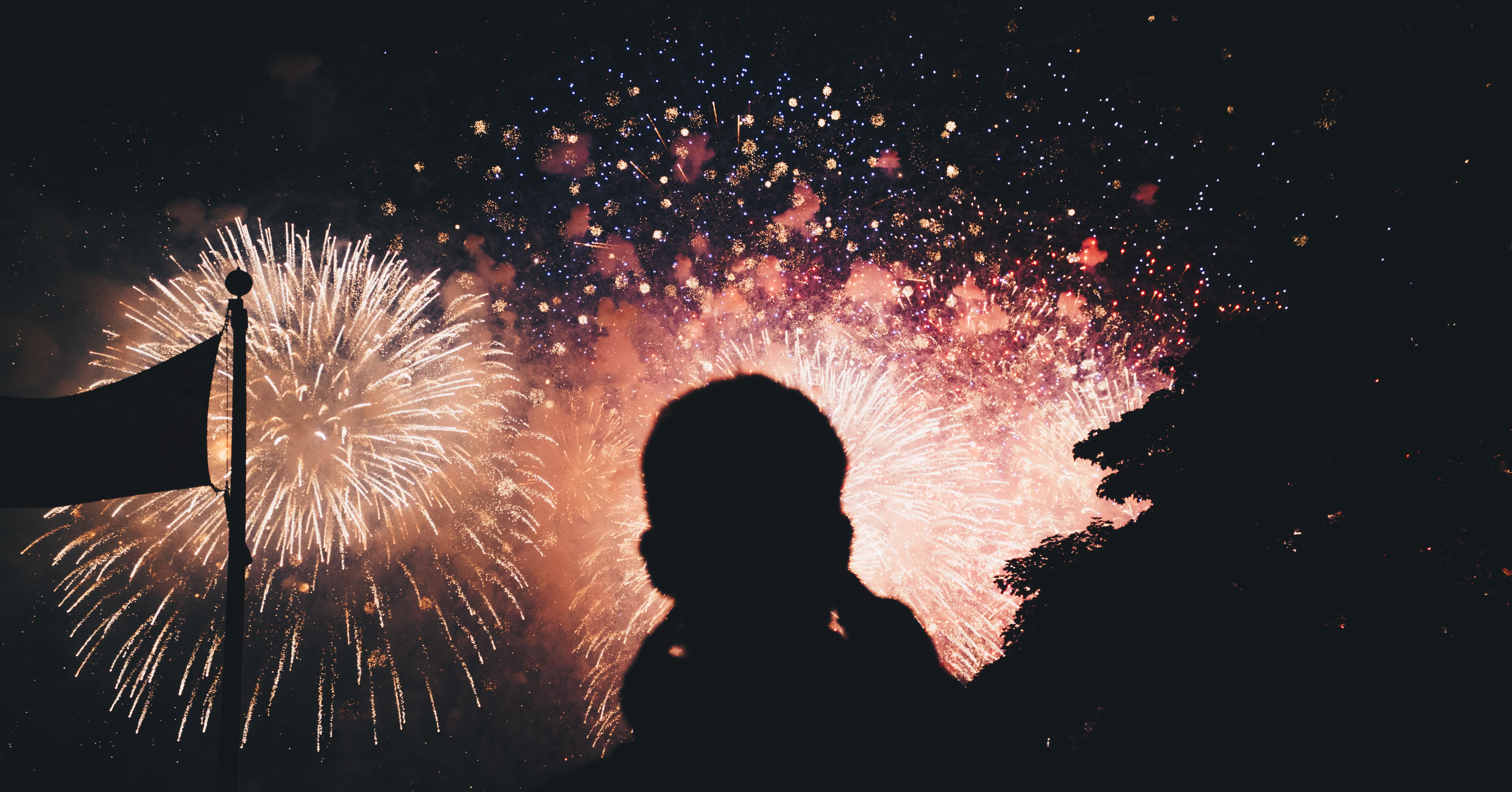Silhouette of a person watching fireworks with a flag HD Wallpaper