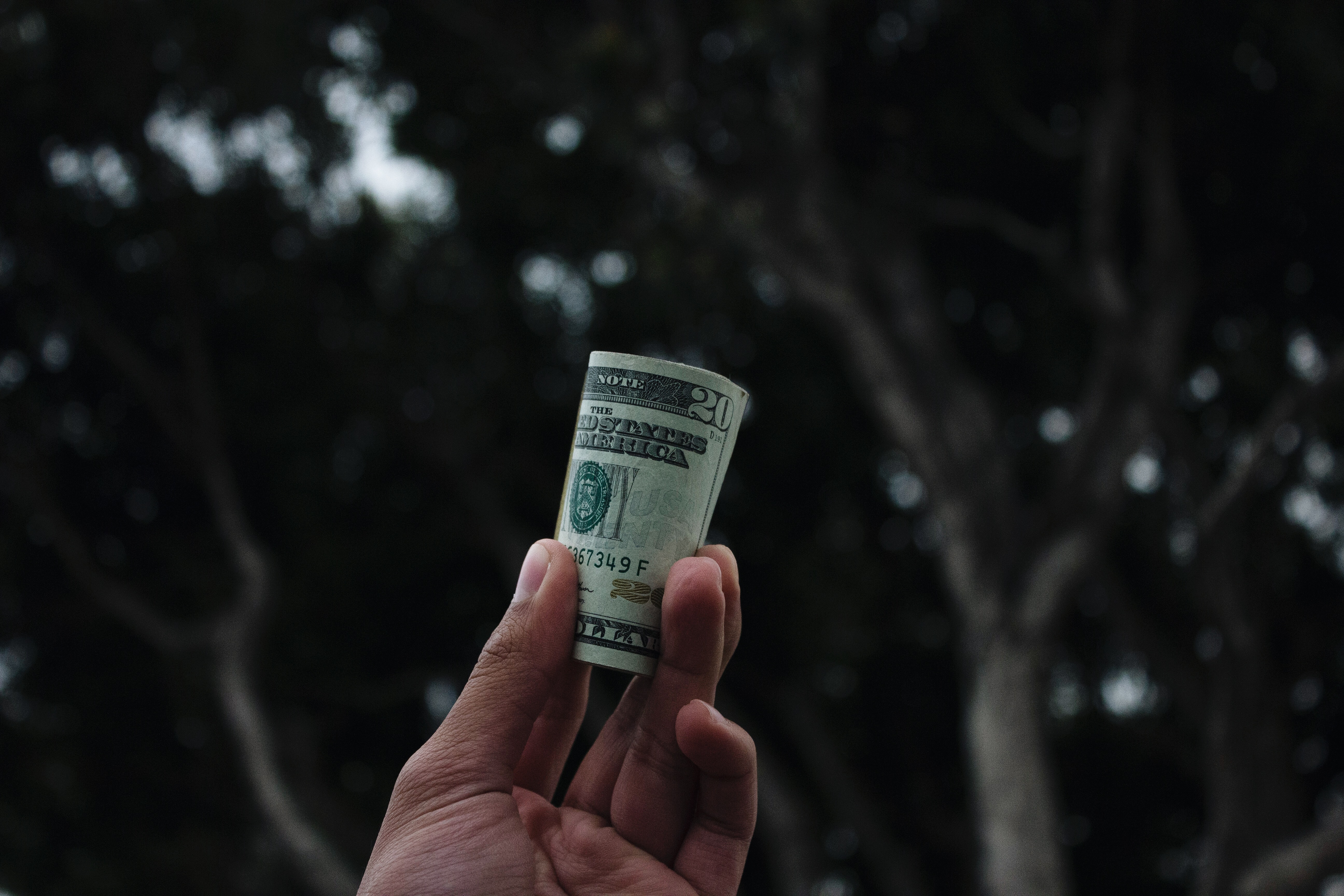 Hand holding a rolled up twenty dollar bill HD Wallpaper