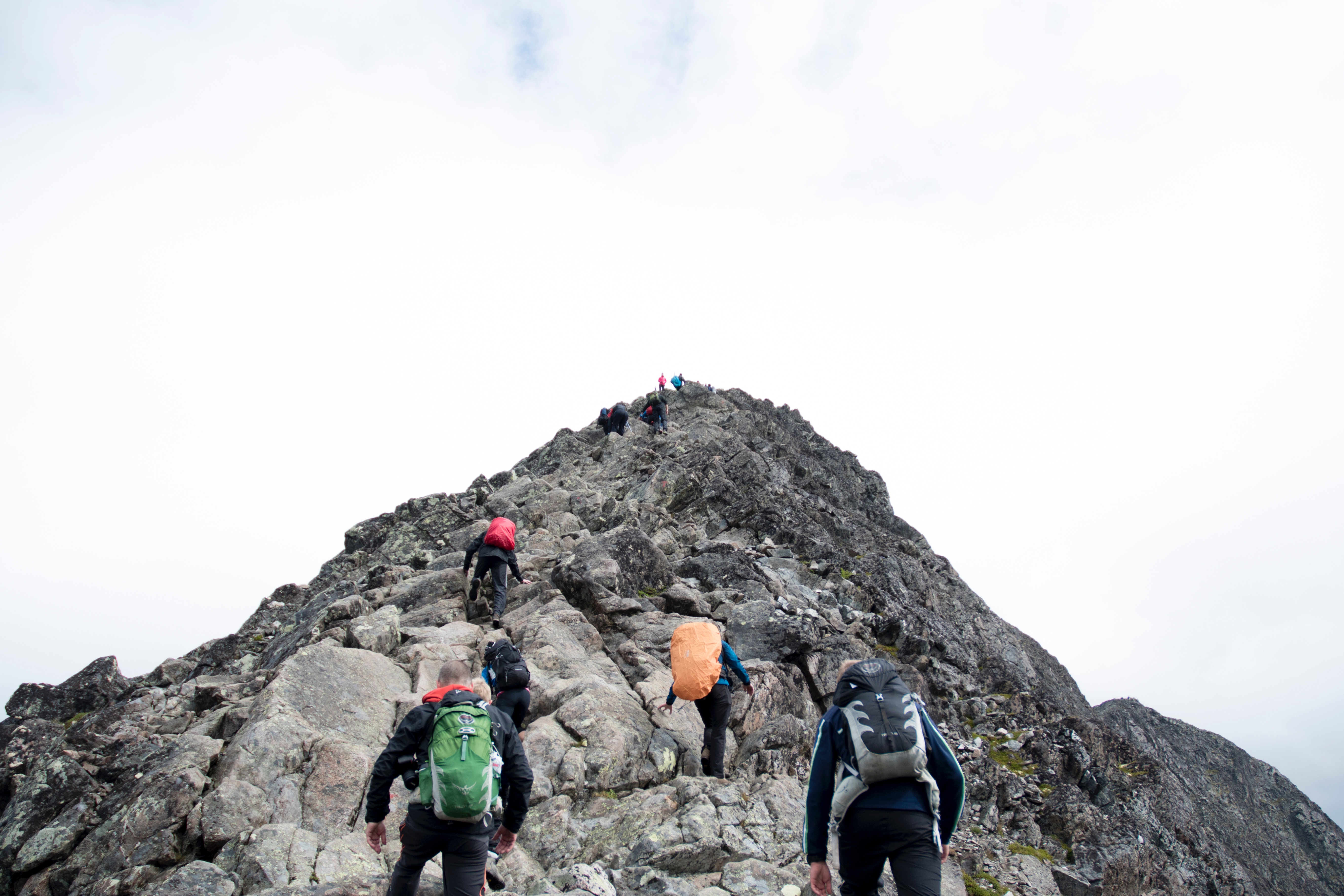Group of hikers ascending a rocky mountain peak HD Wallpaper
