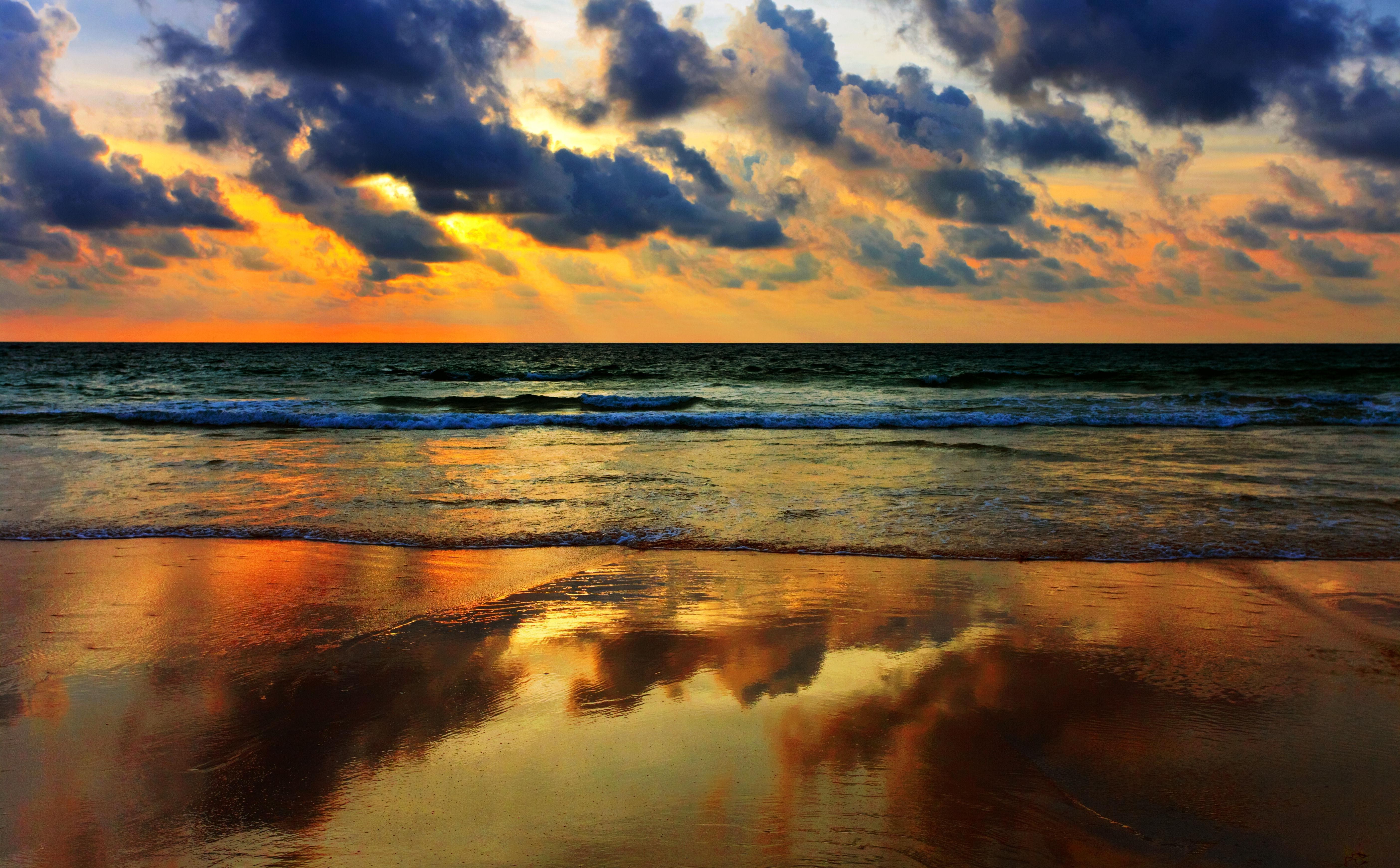 Sunset over the ocean with dramatic clouds and reflection HD Wallpaper