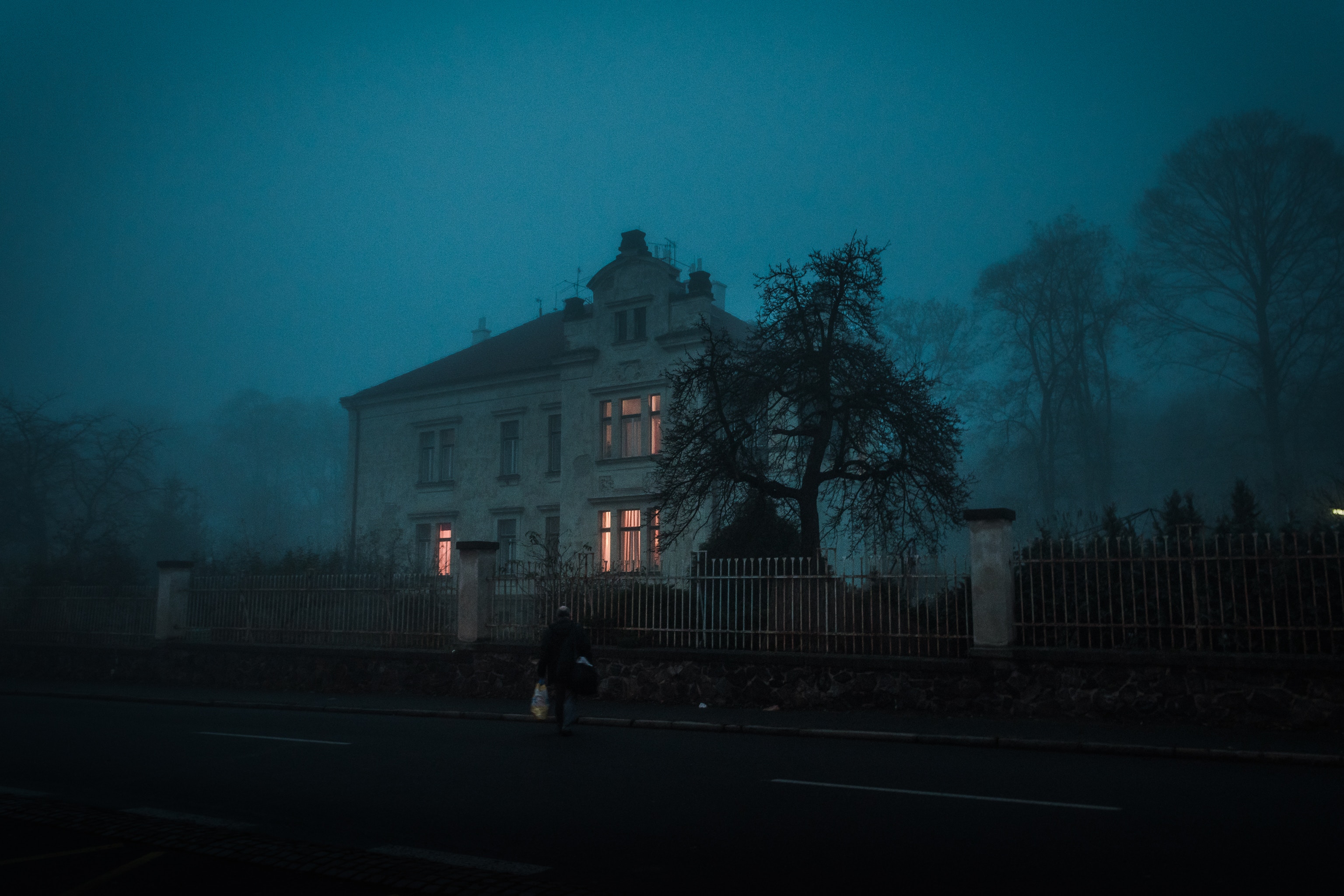 Man walking past a foggy house at night HD Wallpaper