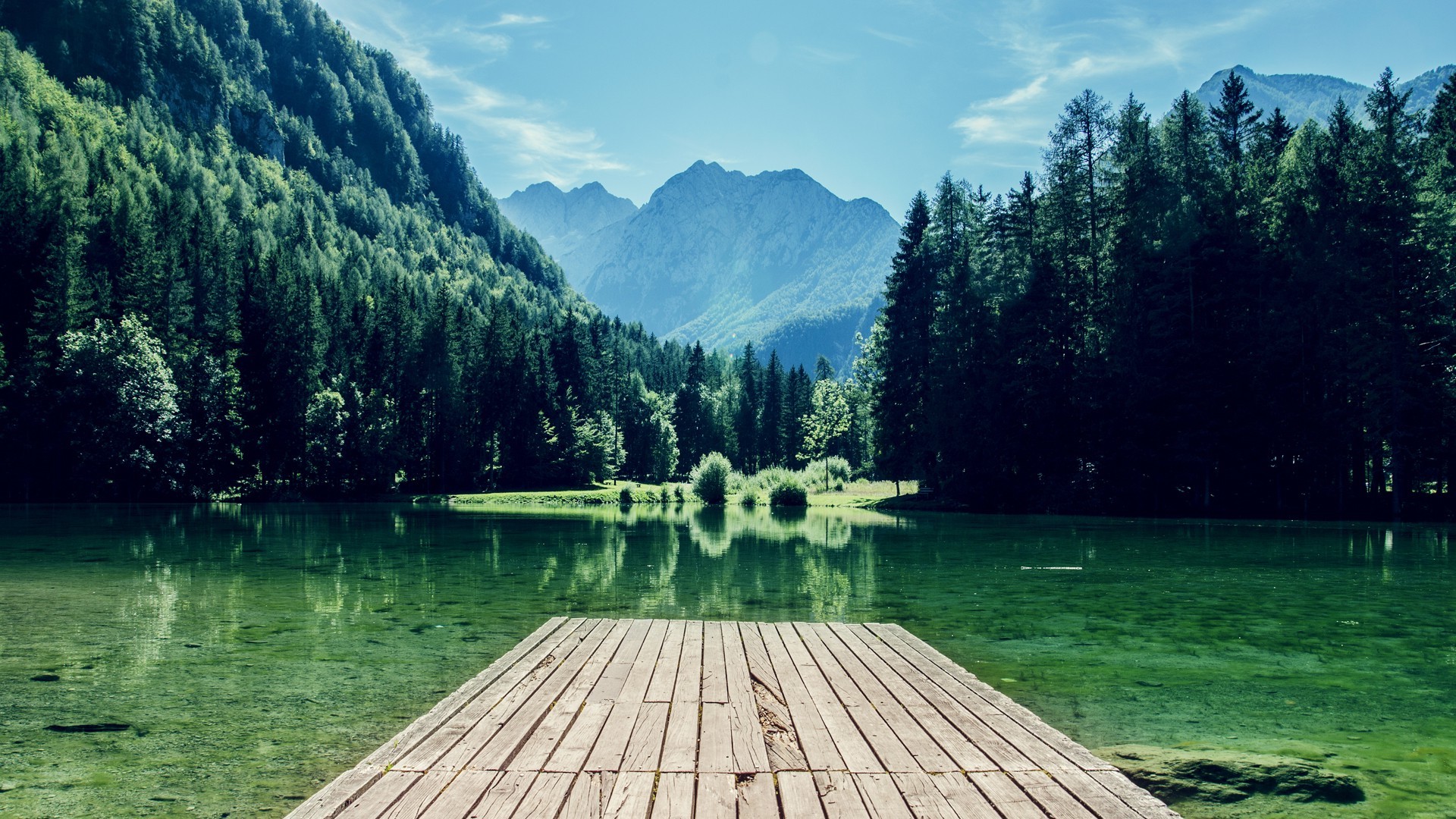 Wooden dock on a clear lake with forest and mountains HD Wallpaper