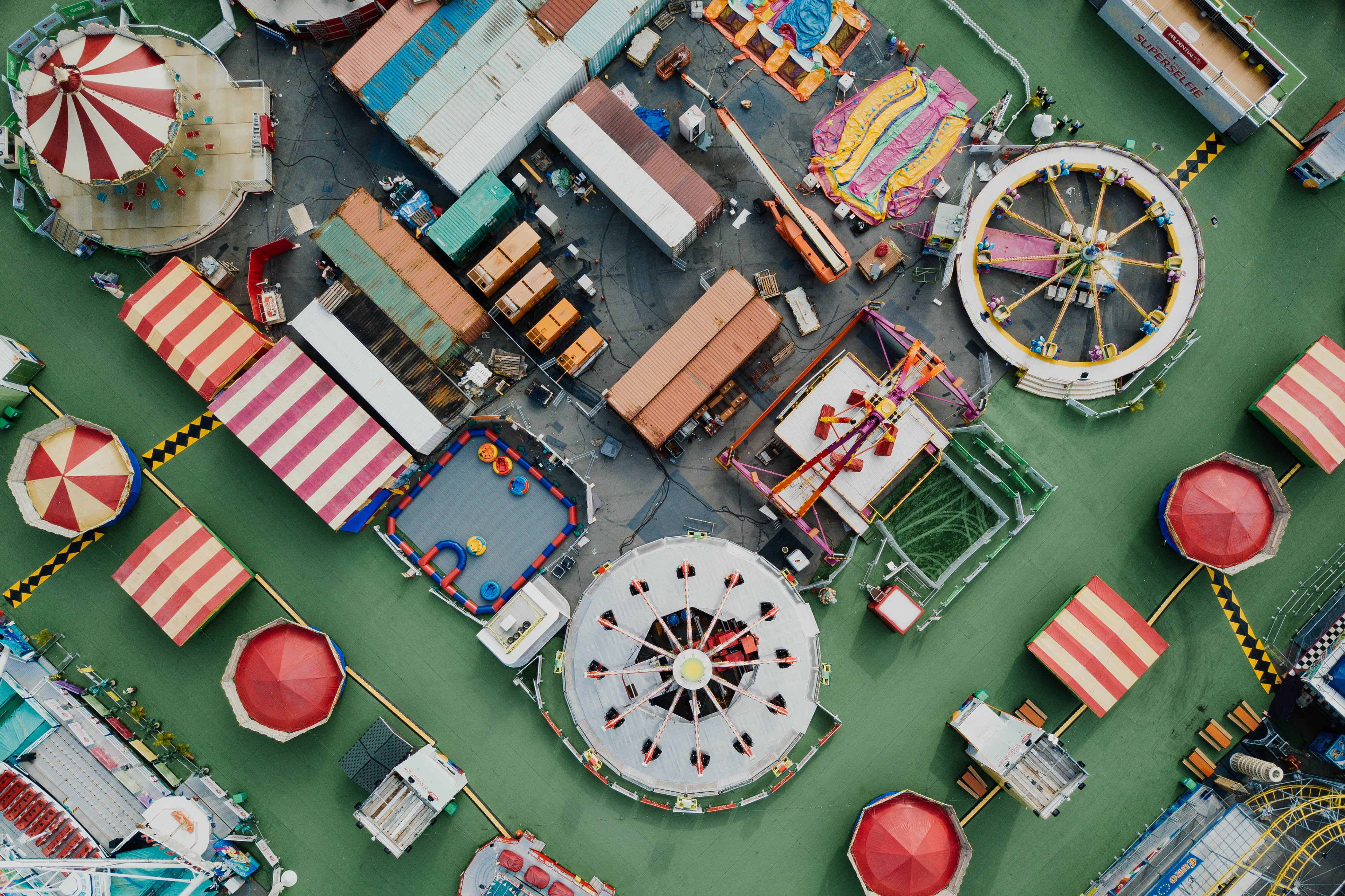 Aerial view of a colorful amusement park with rides and containers HD Wallpaper