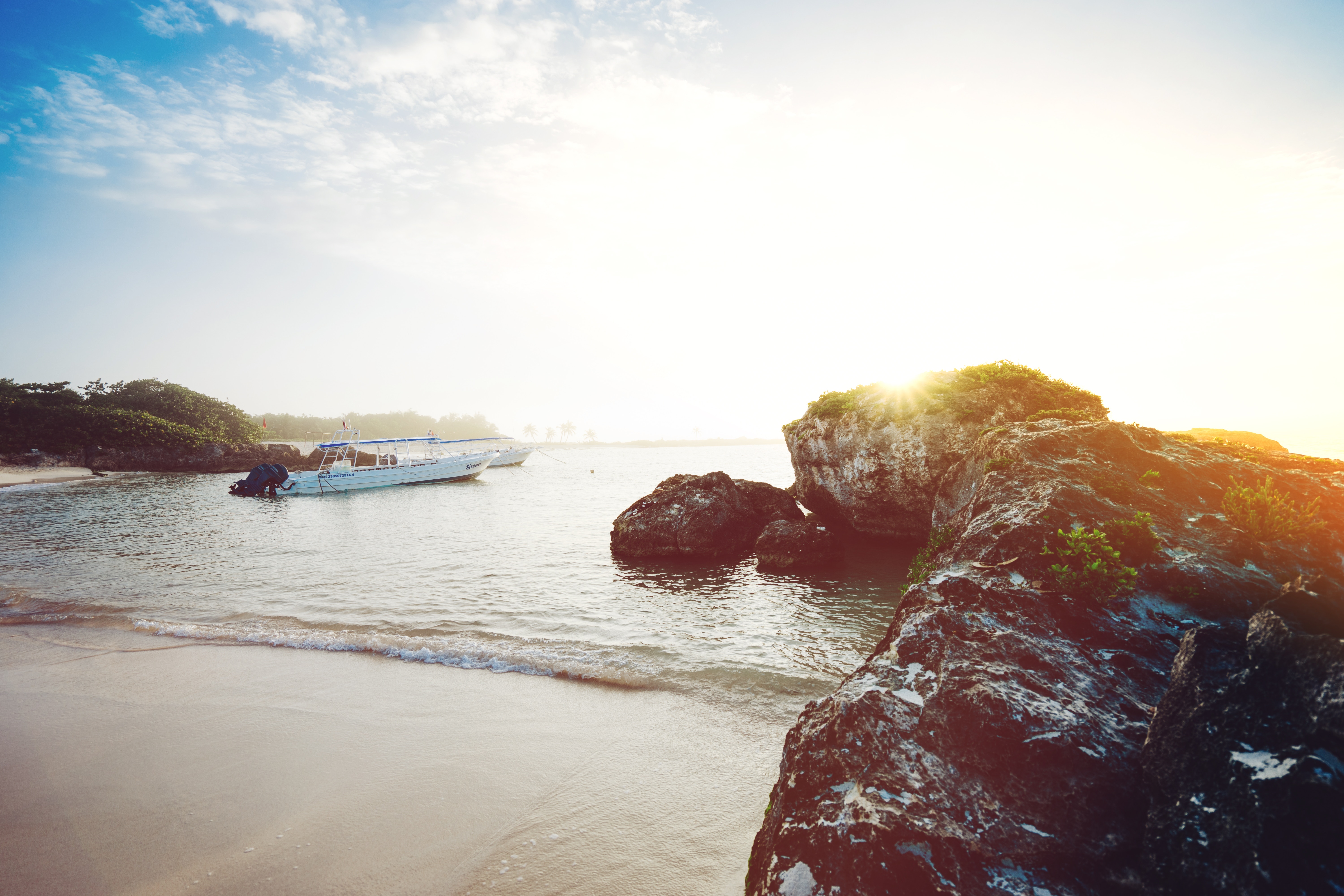 Boats on the water near a rocky coast at sunset HD Wallpaper