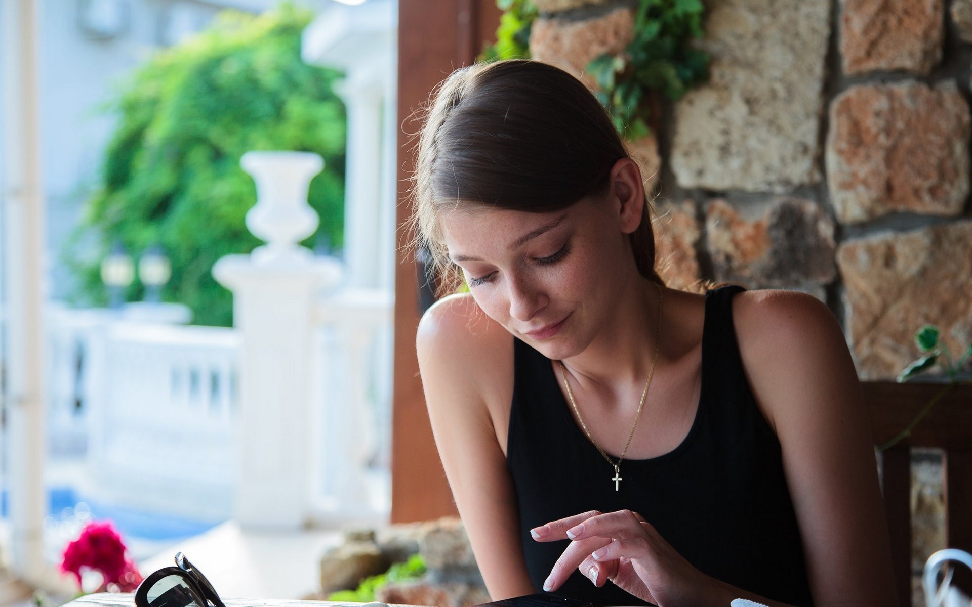 Young woman in black tank top looking at phone HD Wallpaper