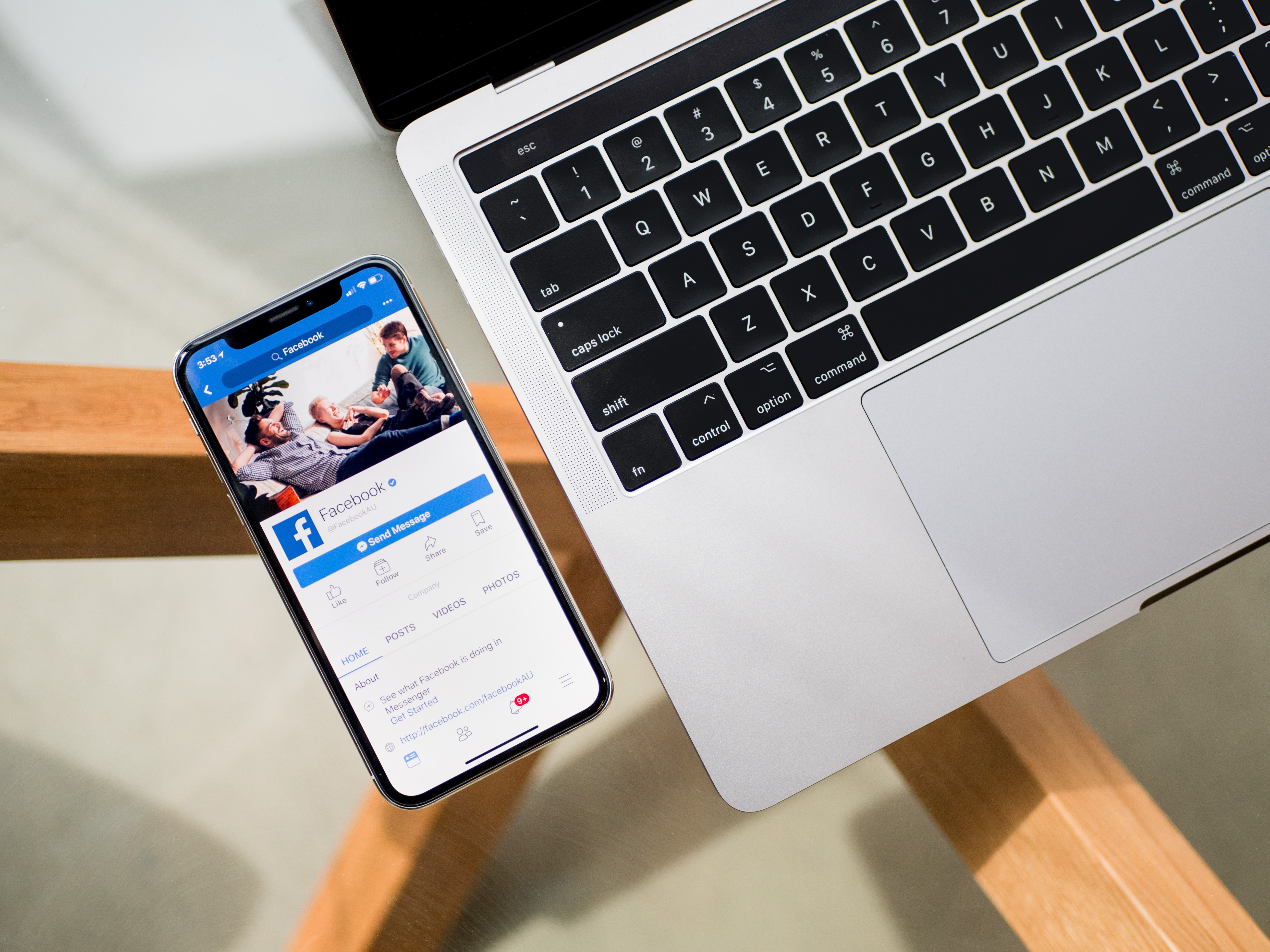 iPhone with Facebook app next to a MacBook HD Wallpaper