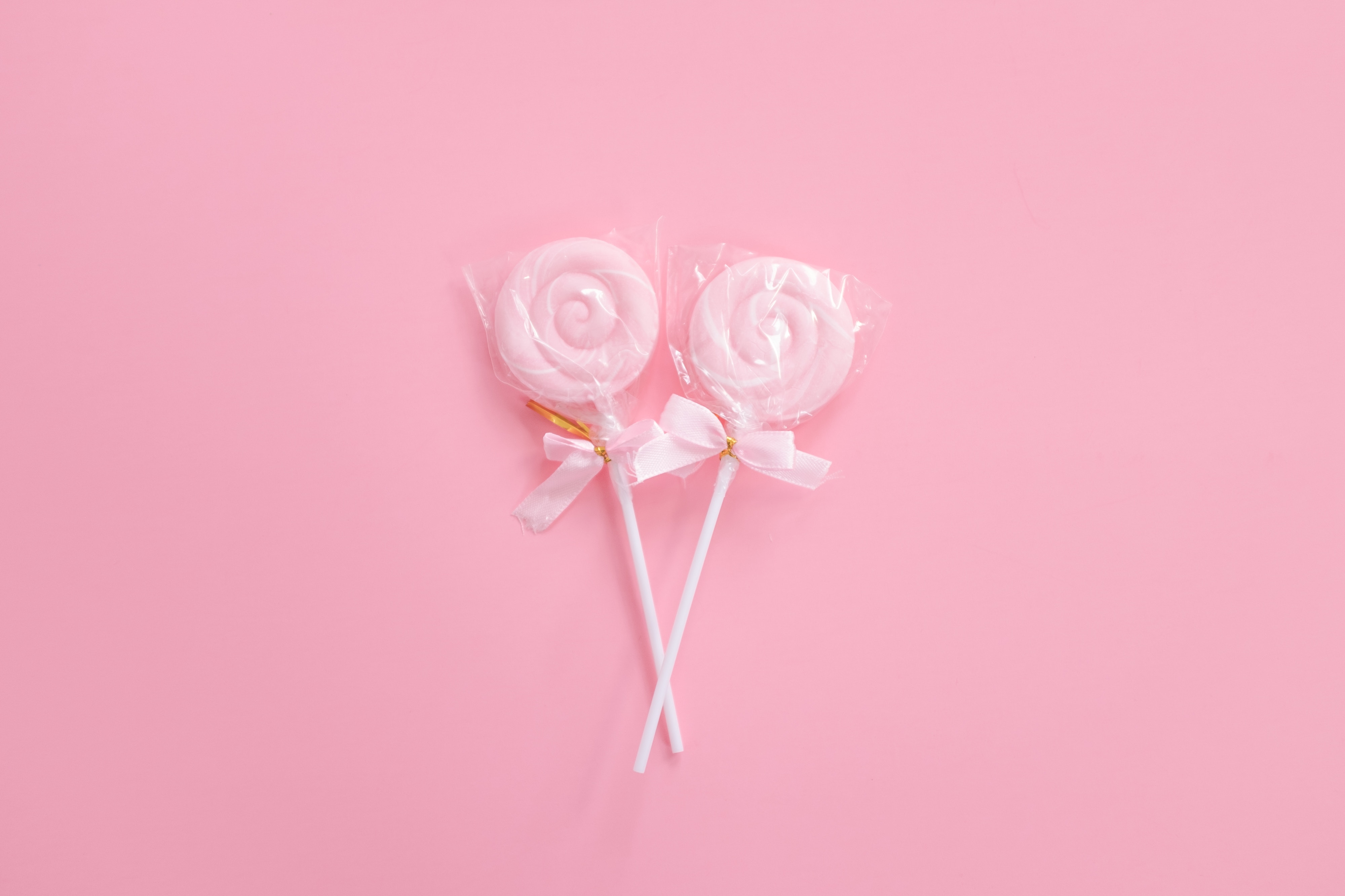 Two pink swirl lollipops with bows on pink background HD Wallpaper